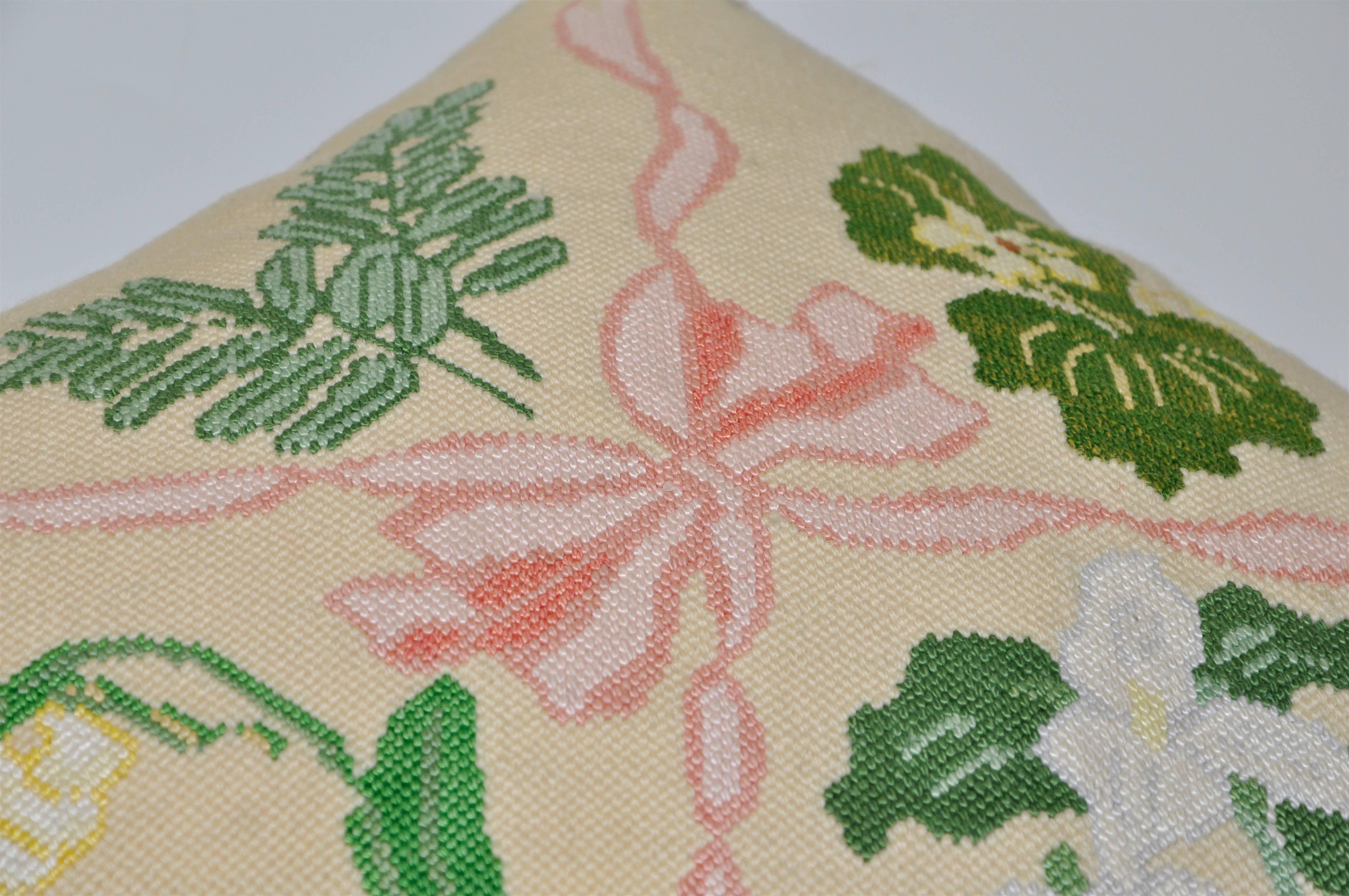 An exquisite piece of antique hand-stitched Irish needlework in a pretty floral pattern of delicate flowers and leaves. In a subtle beige with variety of striking greens entered around a ballet pink ribbon tied in a bow in the middle, this beautiful