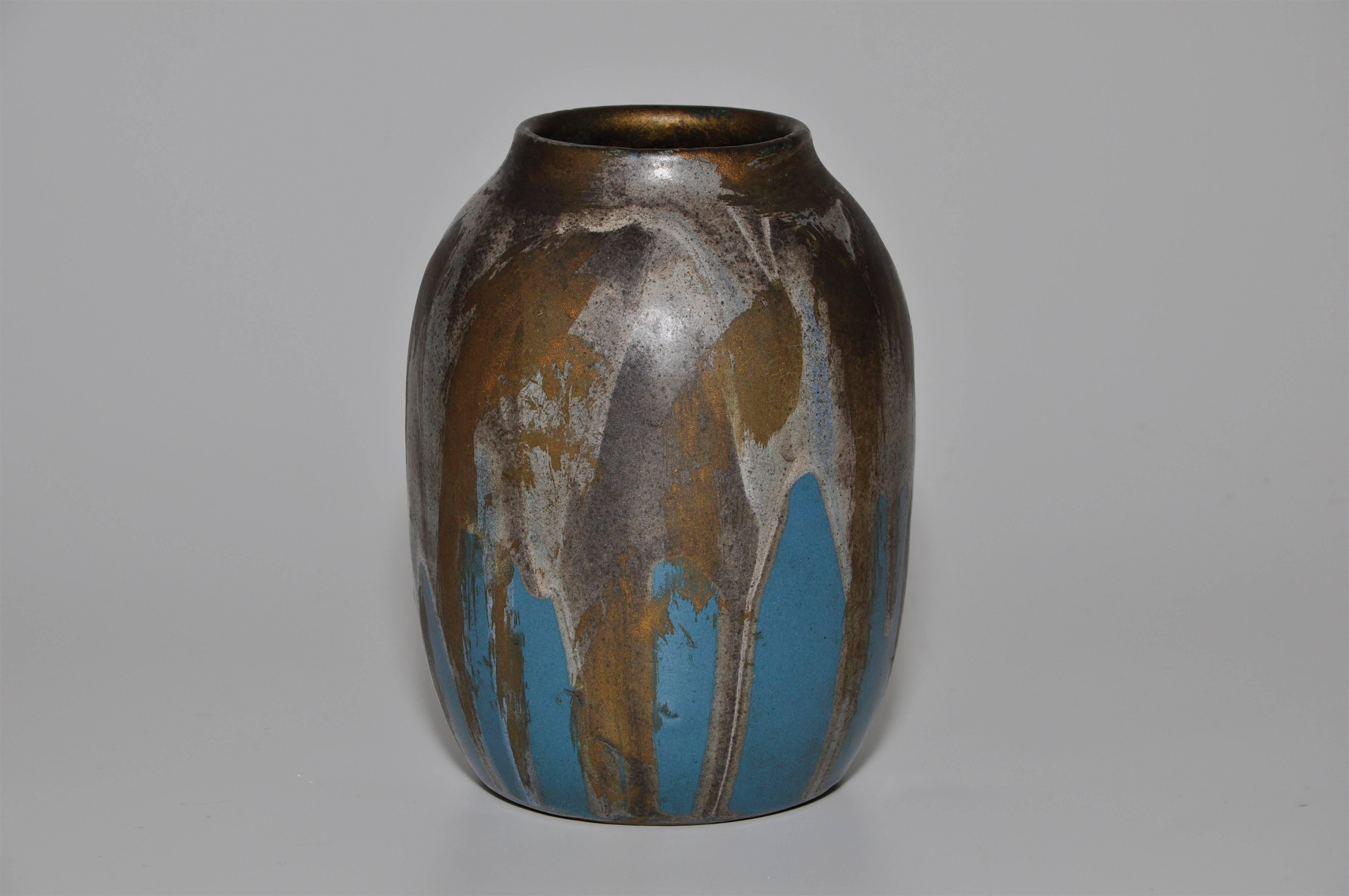 A beautiful piece of stoneware art pottery with painterly stokes of bronze gold brushed over a dripped white glaze on a rich blue base. He worked alongside his father before taking over the studio and acquiring the same style. The rim is a superb
