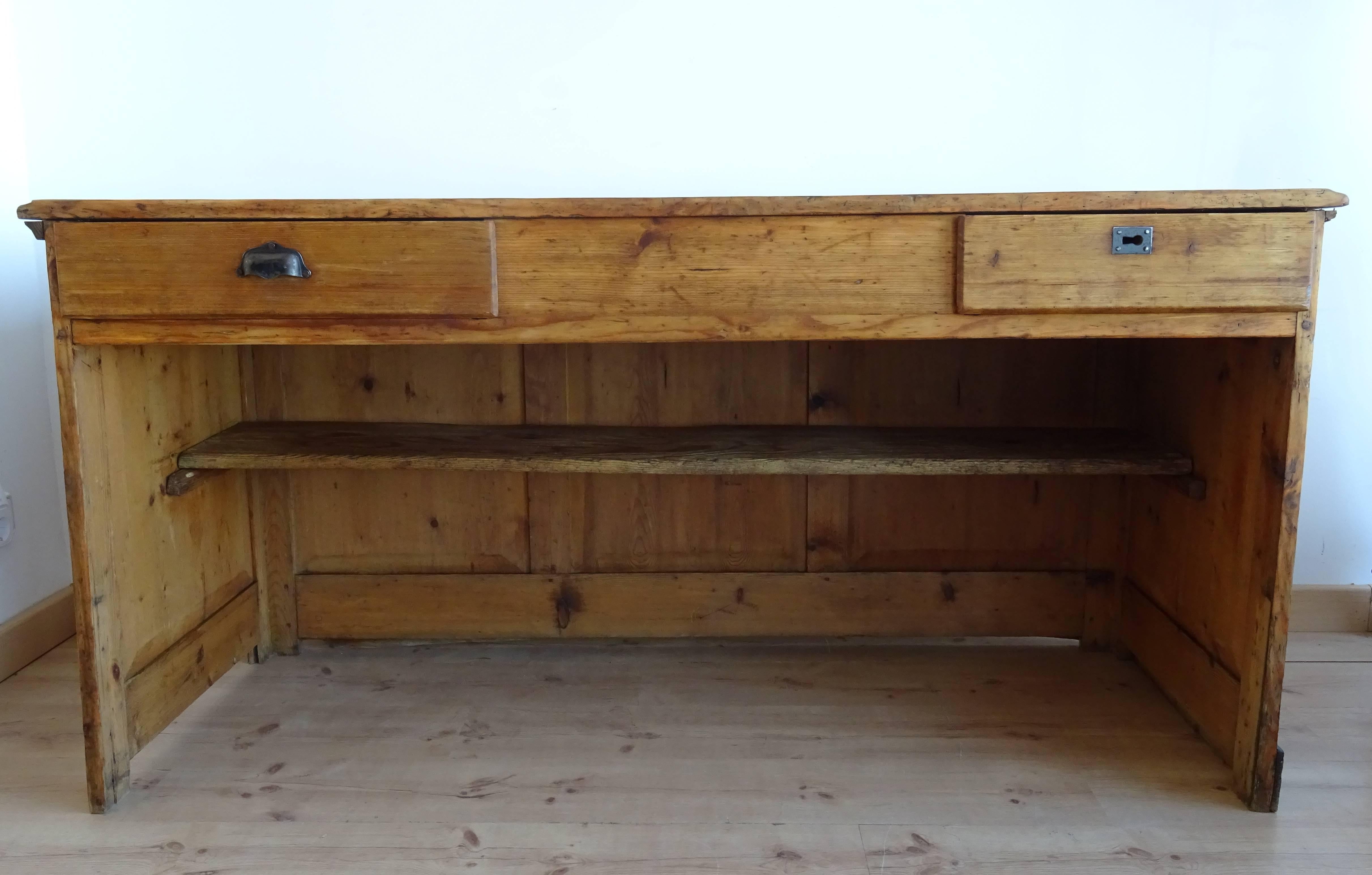 Vintage counter originated from a shop in France in the early 20th century. It is made from pine and features two drawers and a low shelving unit. It is in very good vintage condition with some signs of wear consistent with age and use. Please see
