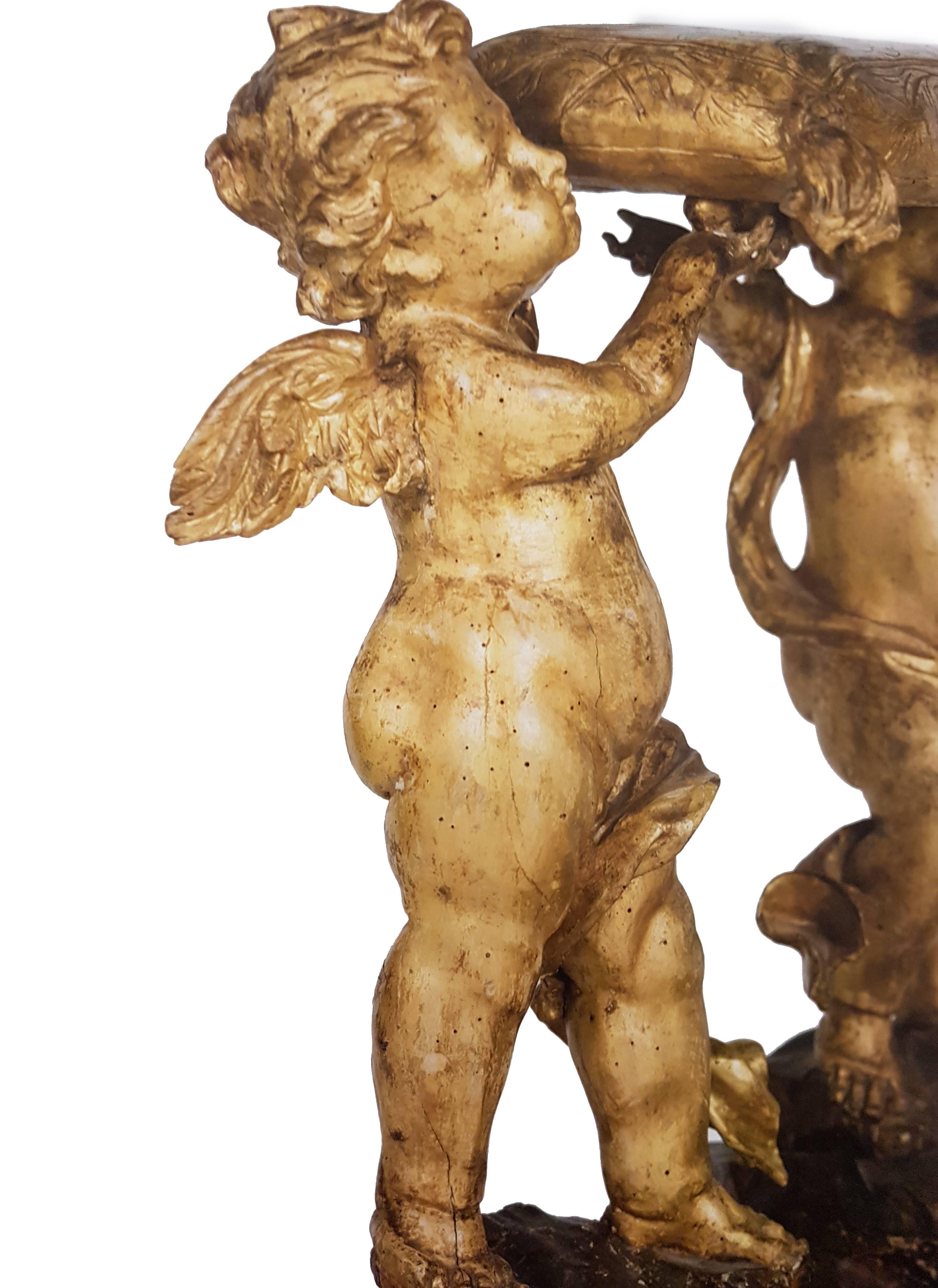 A lacquered faldstool in sculpted and gilded wood, with sculpted winged cherubs upholding a tasseled cushion.

Genoa, late 17th-early 18th century.