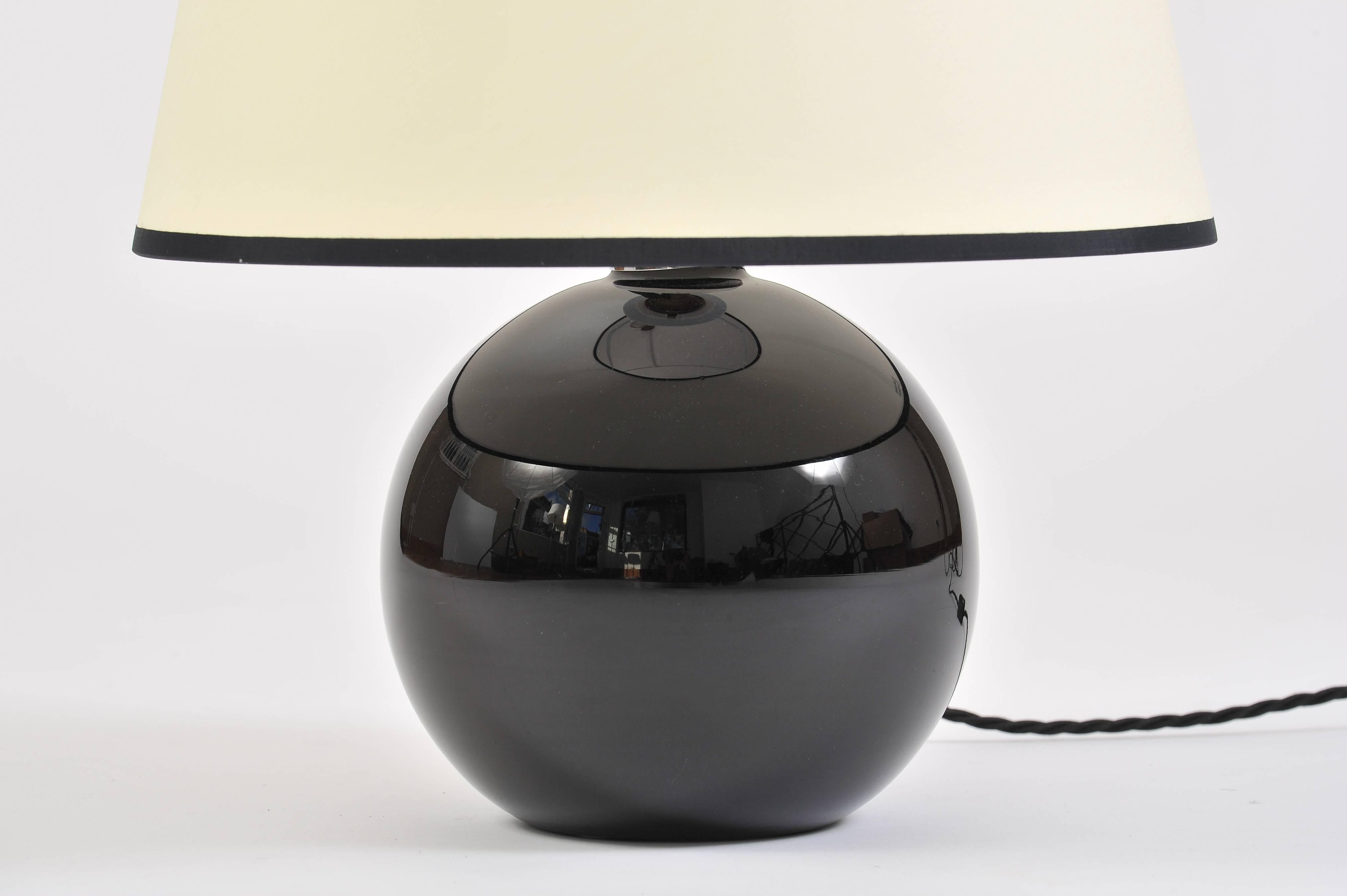 A black glass sphere table lamp in the manner of Jacques Adnet (1901-1984)
With a bespoke black edged ivory fabric tapered shade
France, circa 1950.
