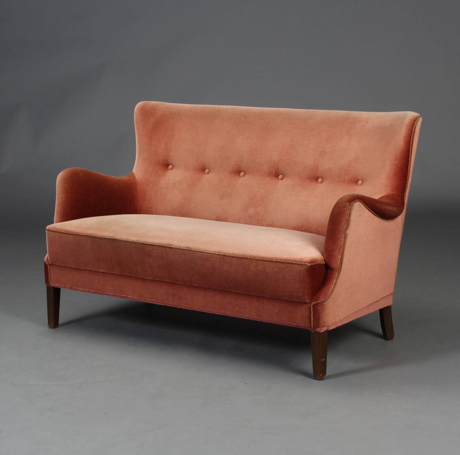 A two-seat 'loveseat' buttoned sofa, in its original mohair velvet upholstery, on four tapering tinted beechwood legs,
Sweden, circa 1940.