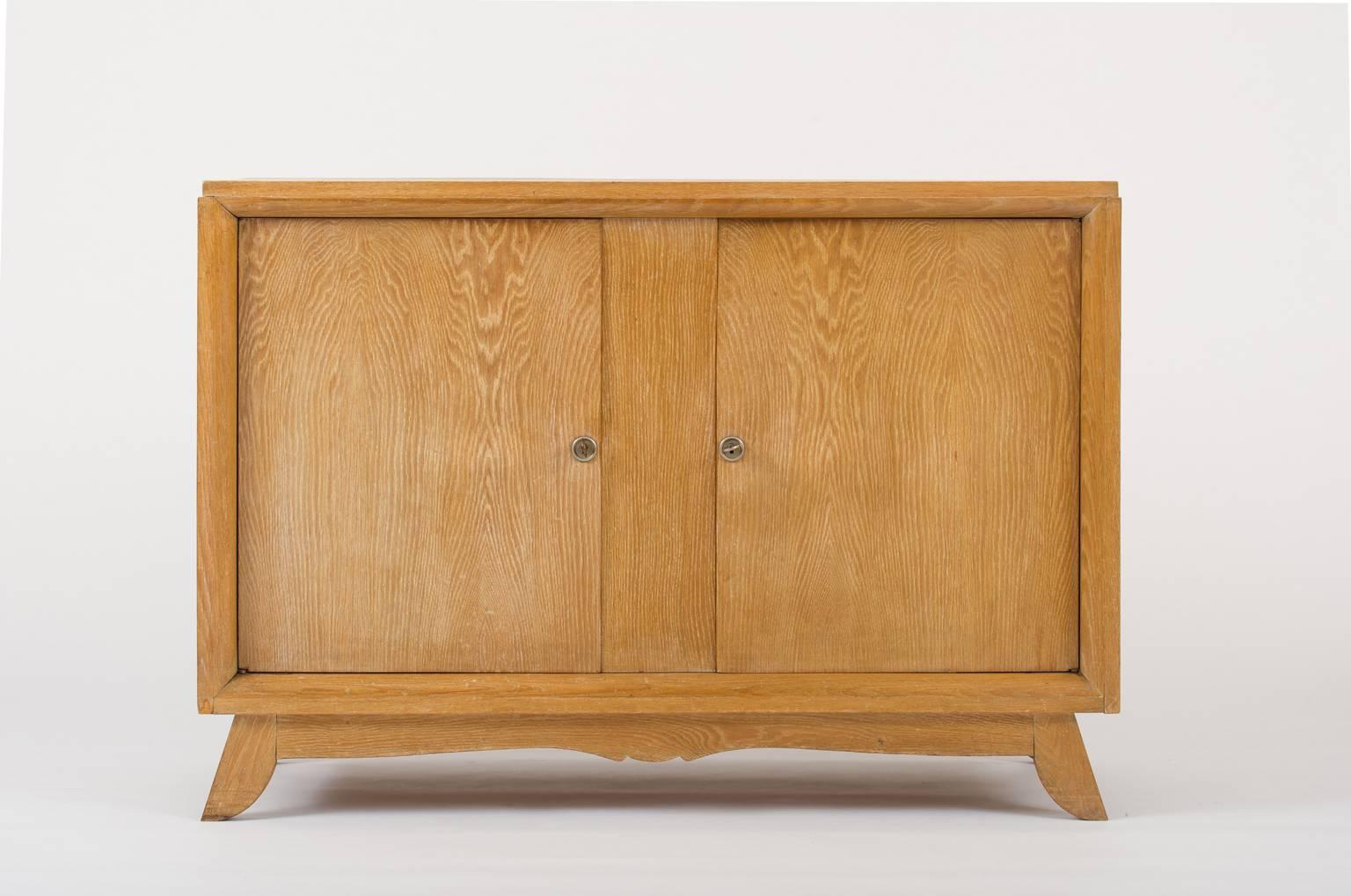 A limed oak buffet, opening with two doors, revealing a central shelf, with its two original keys
France, circa 1940.