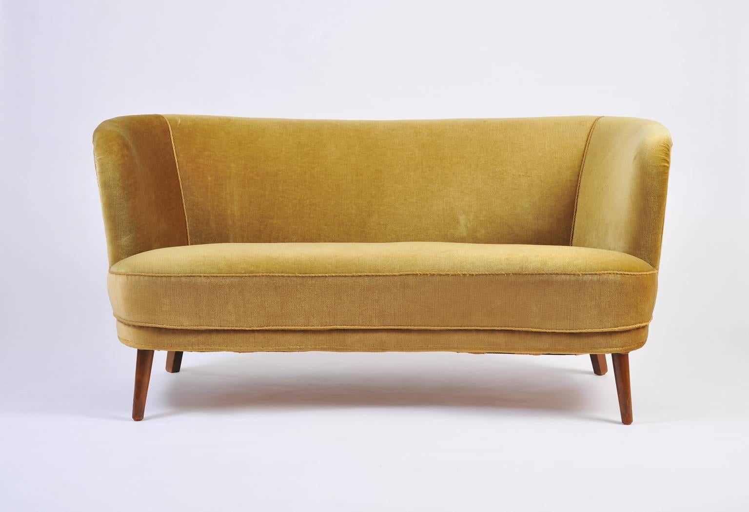 A curved sofa, in its original mohair velvet upholstery, on four tapered beechwood legs
Sweden, circa 1940.