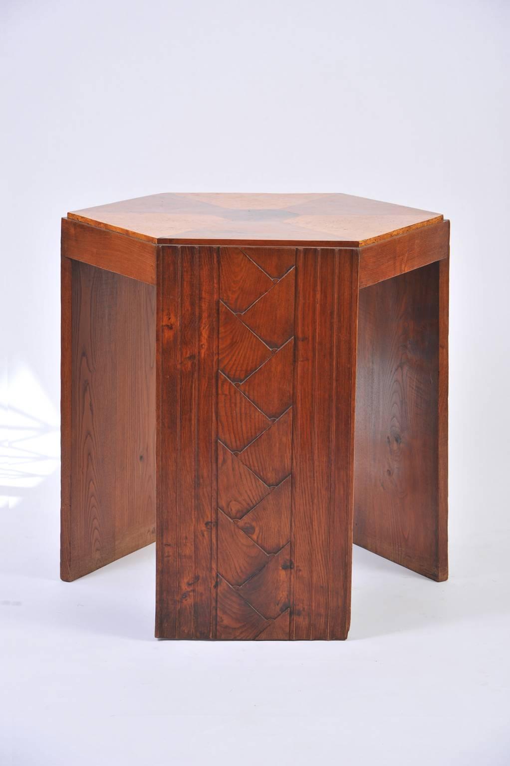 A truly unusual Art Deco walnut hexagonal guéridon table, the 'gradin' stepped walnut and burr walnut veneered top resting on three sides, bearing exquisite stylized scales and thin moldings.
France, circa 1930.