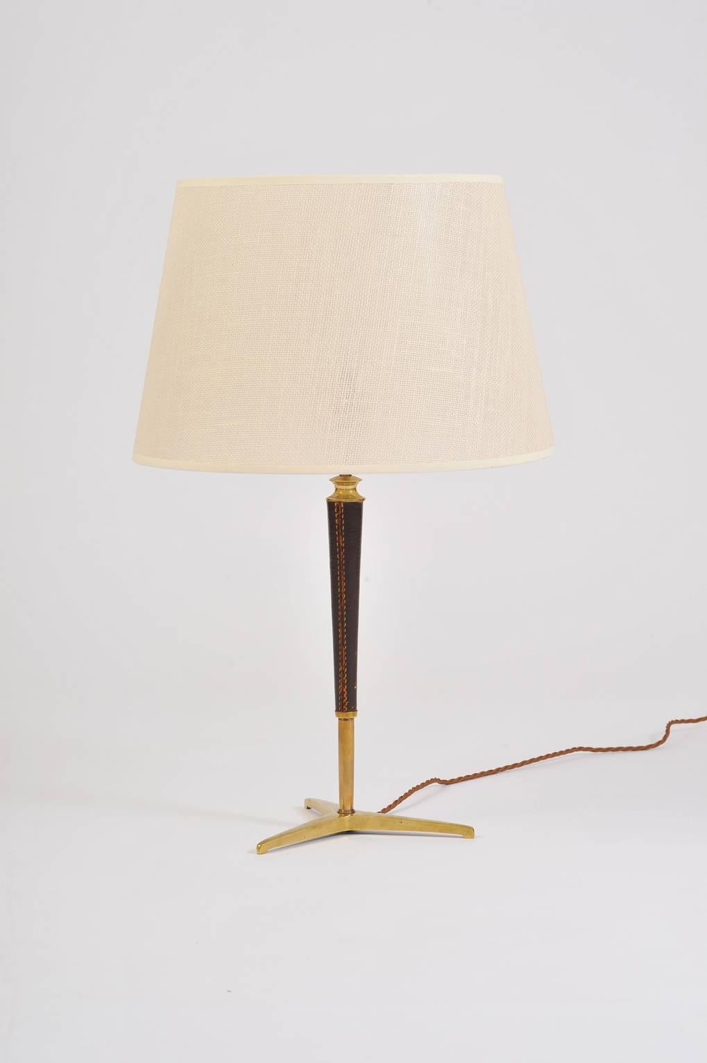 A brass and stitched brown leather table lamp, in the manner of Jacques Adnet (1901-1984)
With a bespoke textured fabric shade
France, circa 1950.
