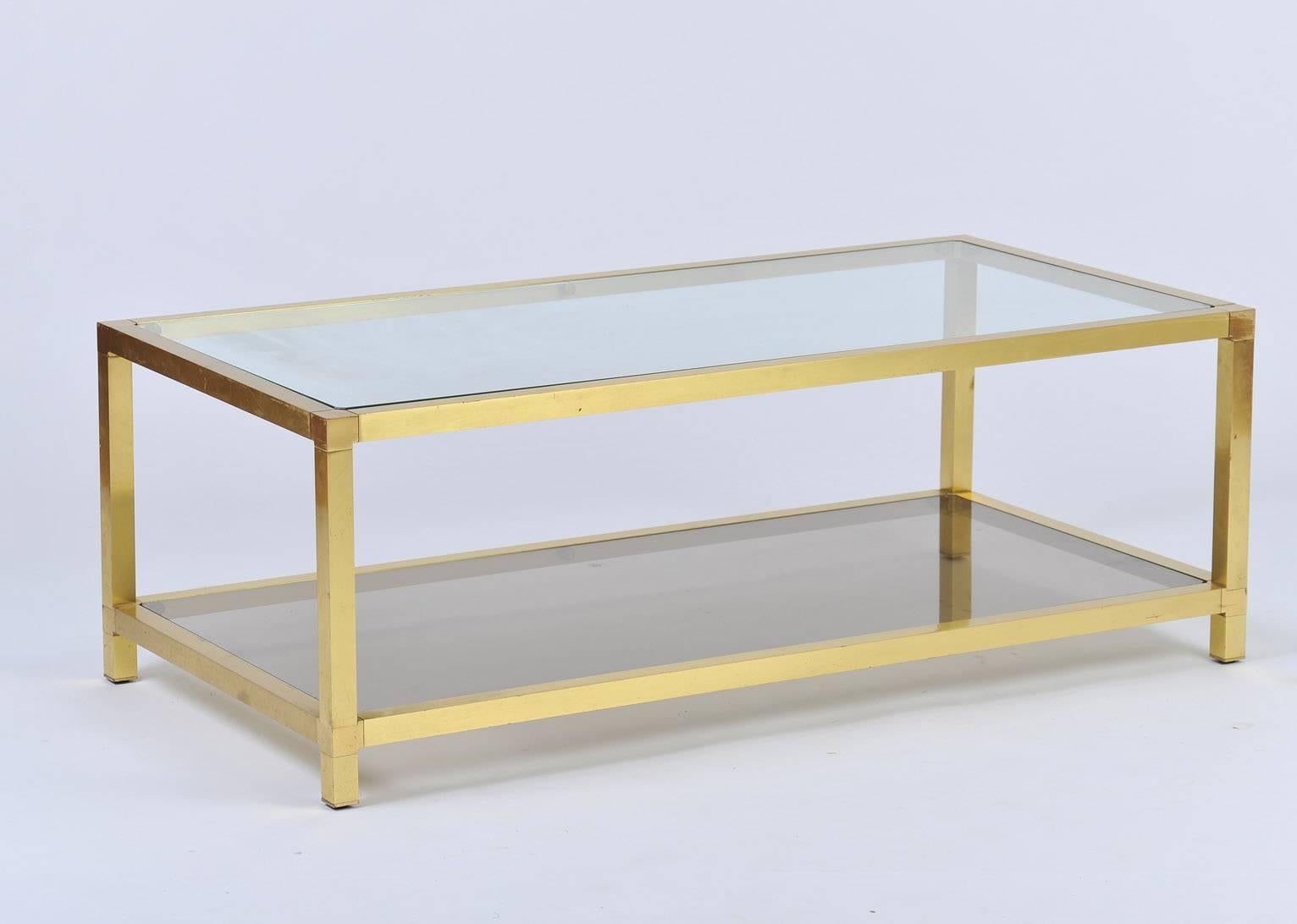 A glass top two-tiered gilt coffee table the bottom shelf of bronze mirror glass
France, circa 1970.