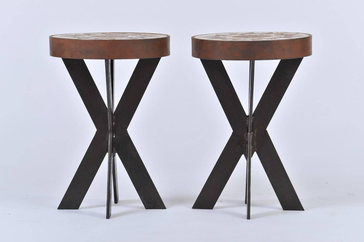 A pair of ceramic top iron stools (or side tables), the quadripod iron bases supporting circular hand painted polychrome ceramic tops
France, Circa 1960
3 available in total (one pair and a single, see other listing to view the single one)