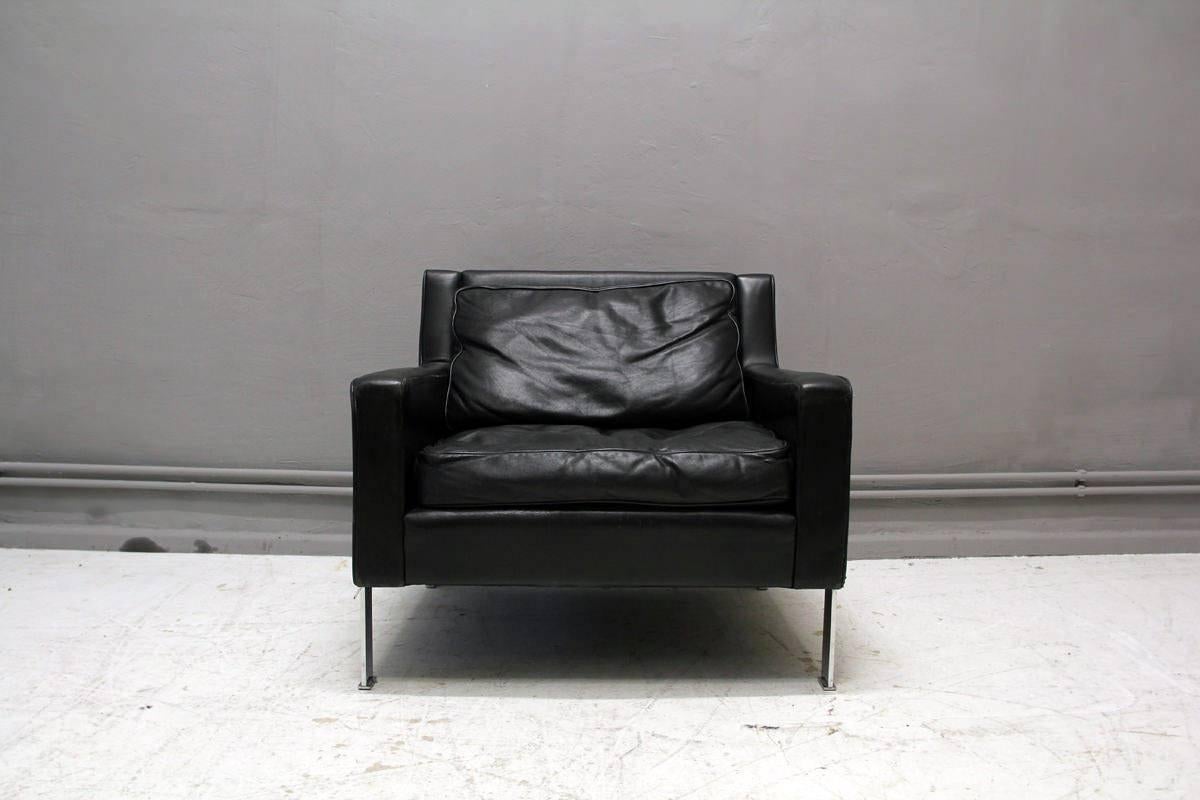 This armchair was designed by Hans Konecke in 1965 for Tecta. It features legs made from flat steel, cushions with down filling and is upholstered with black aniline leather. The chair is in a very good vintage condition with only minor signs of use