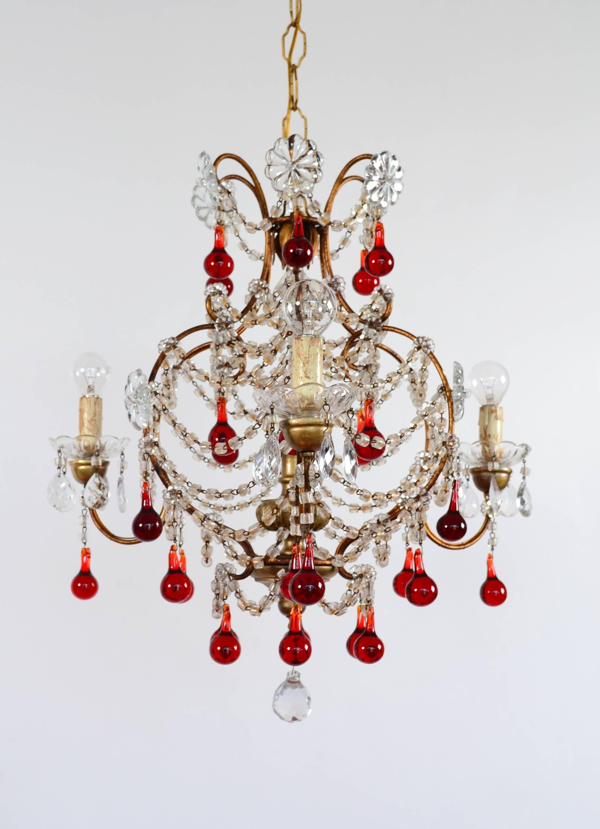 Beautiful Italian chandelier with 30 shiny red glass drops from Murano in perfect shape.
The lamp's frame is made of golden gilded iron and three projecting arms, holding wooden parts on which are mounted three glass bowls. Inside the glass bowls