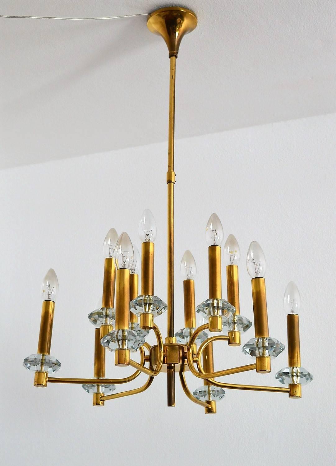 Beautiful and elegant full brass chandelier made in Germany in the 1960s, with six double arms, and on each arm two lights.
The twelve candelabra bulb holders are inserted in long brass pipes, which are positioned on edged glass blocks.
The brass