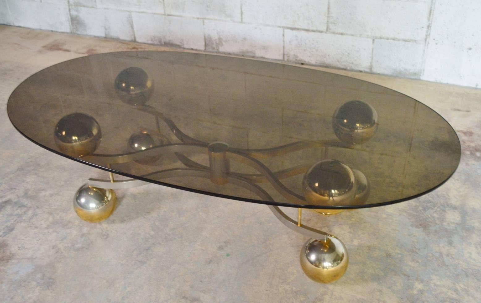 A gorgeous and quite rare large Sputnik or Space Age coffee table made of a solid chrome base, composed of eight round globes, with a light brass finish.
The oval top is smoked glass.
Made in Germany in the 1970s.
Reminds the Space Age style.

 