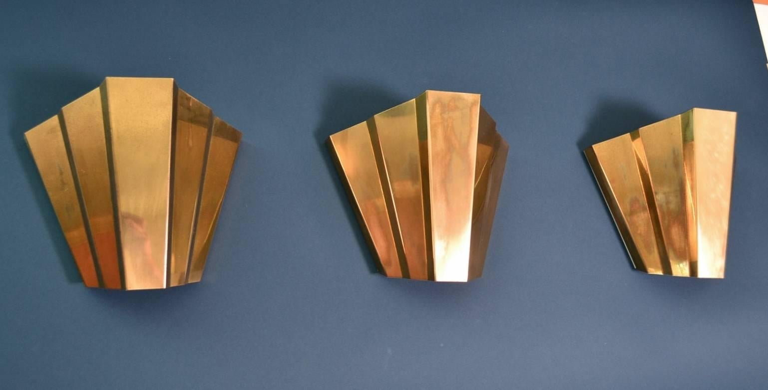 A beautiful set of three shiny brass wall sconces in Art Deco style, made by Egoluce, Italy in the 1980s.
The sconces are painted internally in white color.
Each sconce is equipped with an Edison bulb holder for max. 100W bulbs.
The sconces have