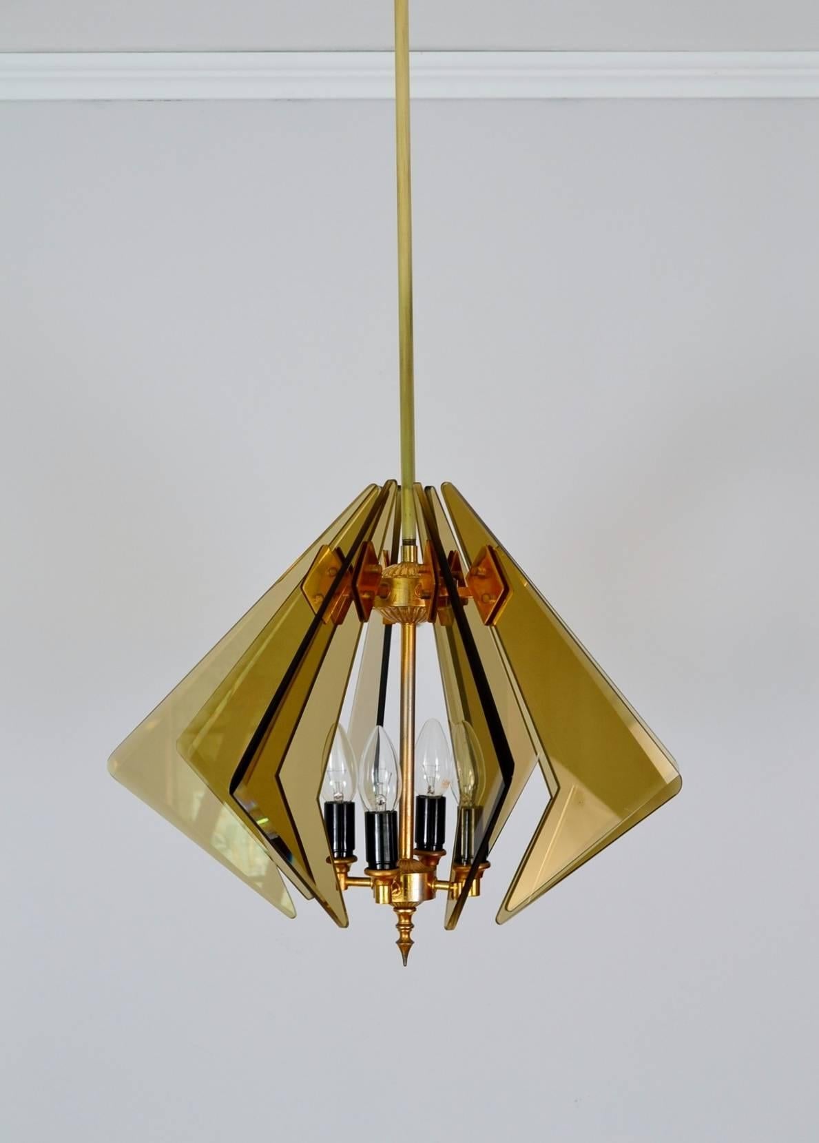 This beautiful Italian chandelier with cut smoked glass and brass details is a real witness of the Italian 1960s by Cristal Art. 
The eight smoke glasses are arranged in a star shape around the four candelabra sized bulbs and the central bar to the