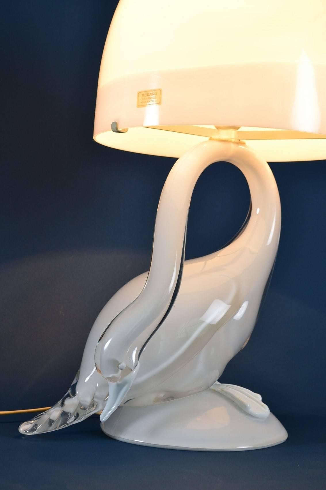A beautiful unique handcrafted artist piece, made in Murano in the Mid-Century, 1960s.
The heavy lamp base in opalescent and shiny white color depicts an elegant swan and is handblown; the lampshade, made of crystal glass too, in mounted on the
