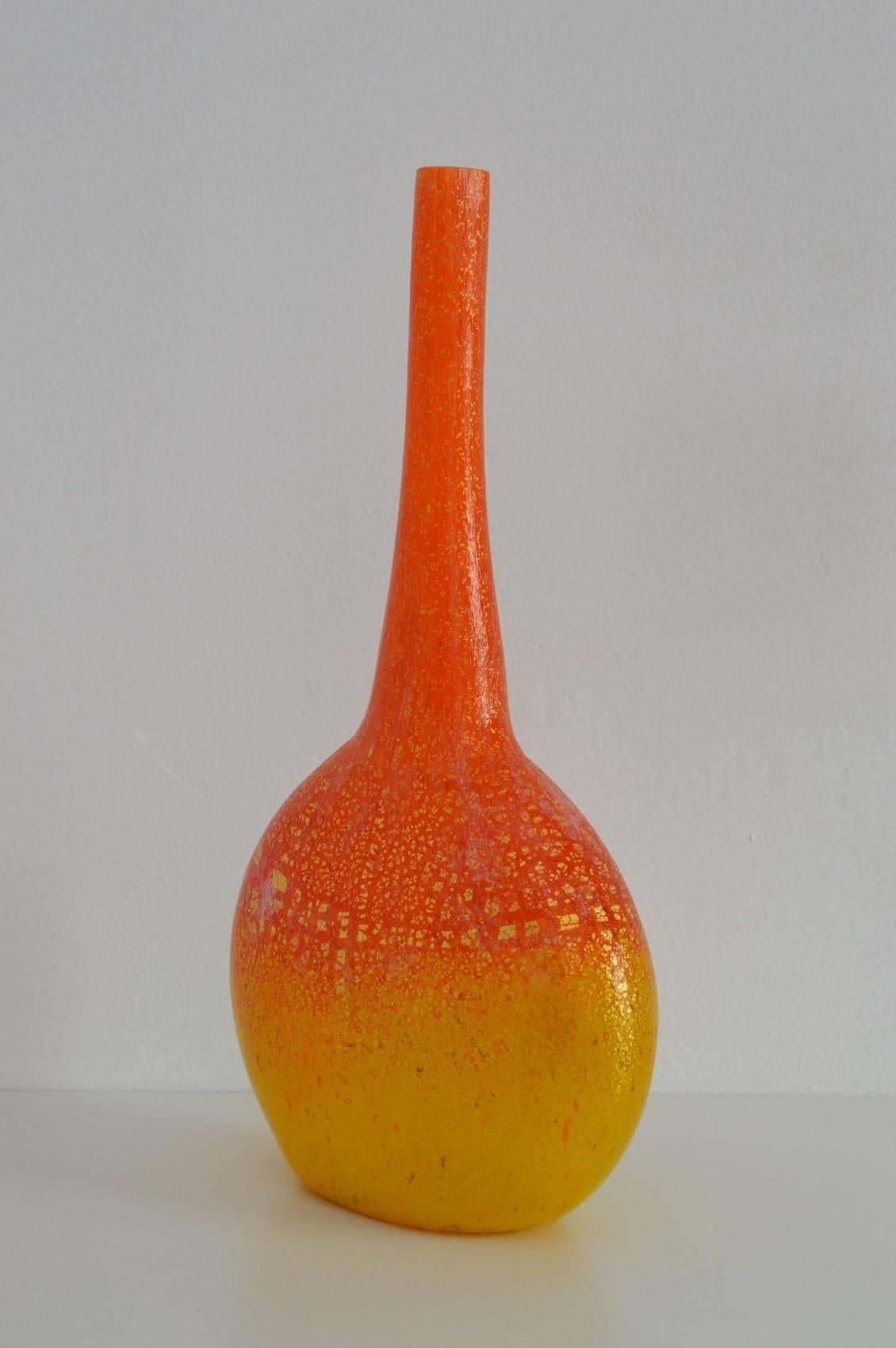 A beautiful and big sized handcrafted Murano vase from glass master Enrico Cammozzo of the 1980s.
The vase has a white inside base and is then covered with orange-yellow glass, which is overall speckled with 18-Karat gold plates. Over the golden