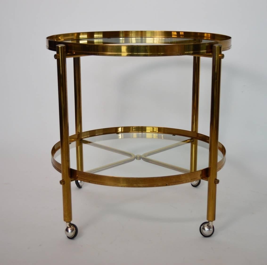 Beautiful Regency-style Italian serving trolley or bar cart from the 1960s with four wheels.
The two trays are made of glass with a beautiful brass frame with stunning patina. The upper tray is removable.
The legs are made of gilded metal.
The