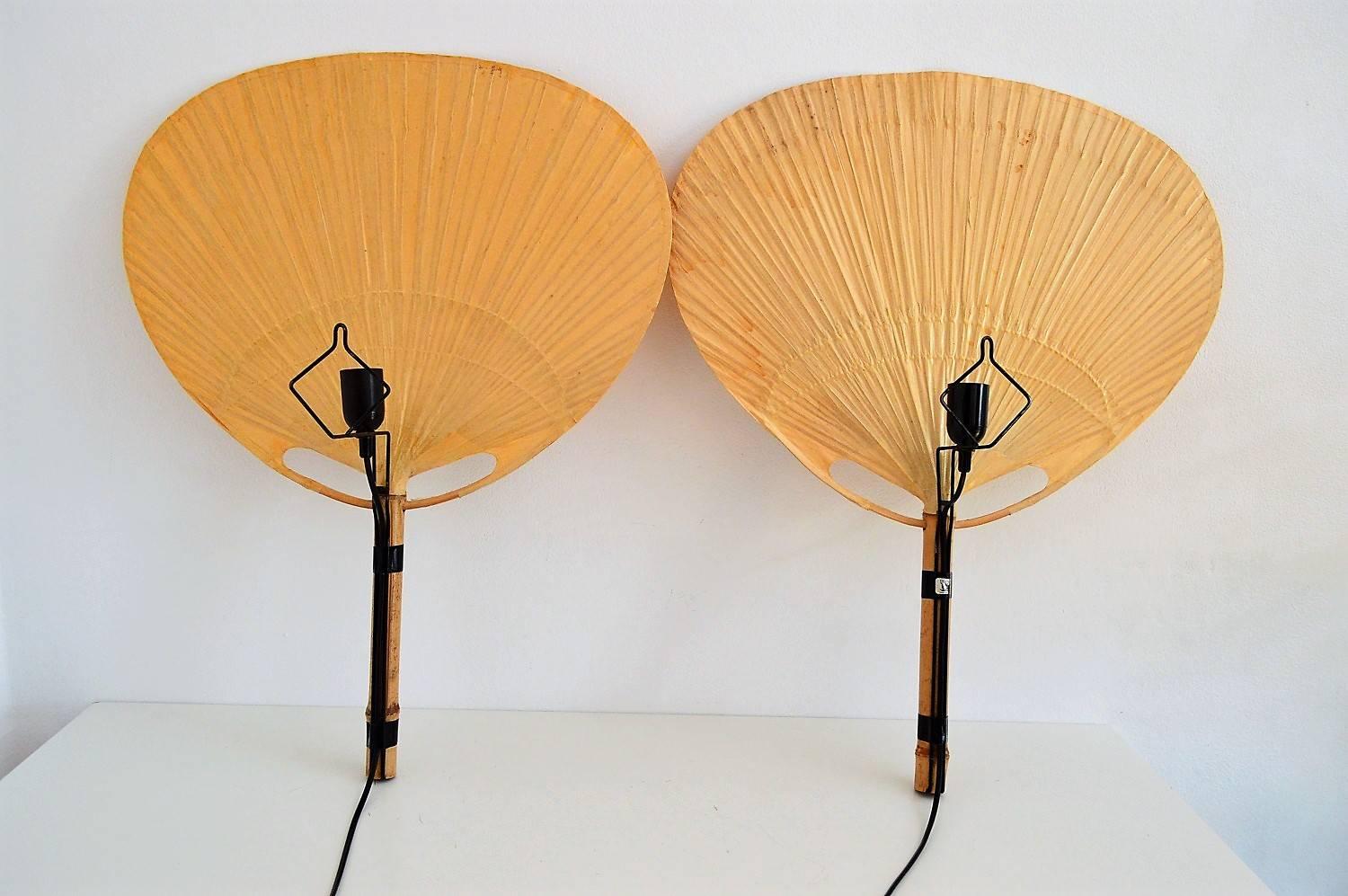 Two pieces of Ingo Maurer big Uchiwa fan lamps with metal holder for wall hanging.
All fans are made of bamboo and rice paper.
The metal holders are equipped with original Edison bulb holders.
The lamps are equipped with black rubber cable for