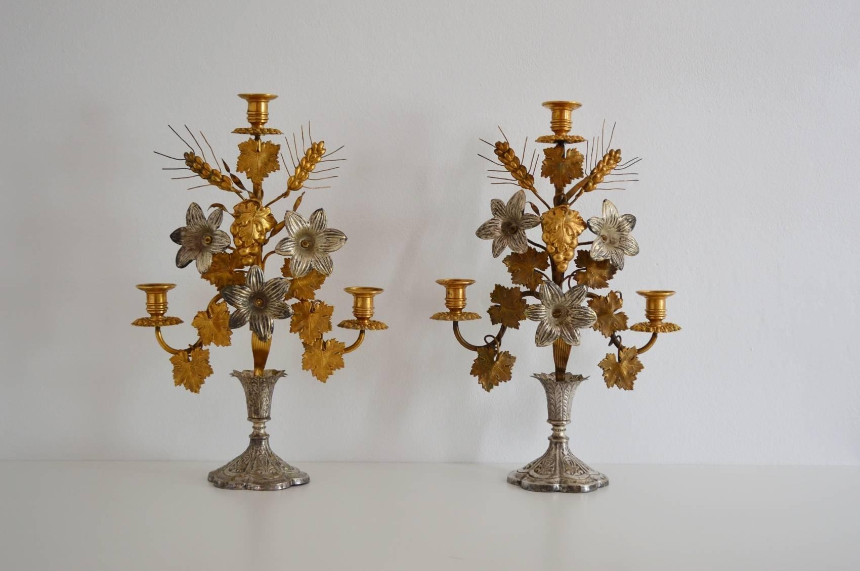 Beautiful pair of antique French candlesticks or candle holders composed of flowers, leafs and wheat and made of different metals as brass, tole and gilt metal.
This kind of candlesticks have been produced to order in the end of the 19th century to