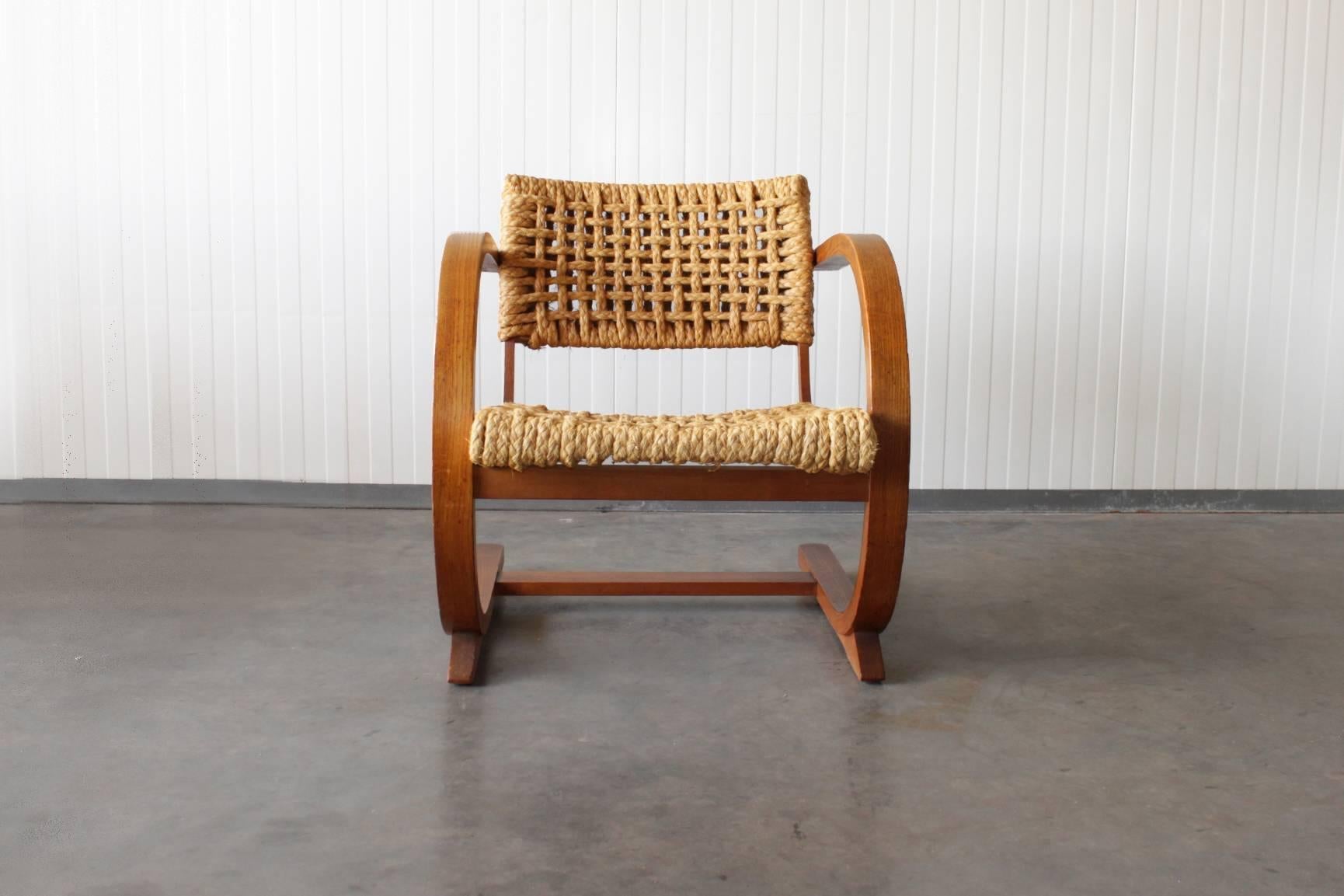 This rare armchair was designed by Dutch designer Bas Van Pelt. It was produced in the Netherlands, circa 1936. The chair features curved oak rails, including armrests and a woven raffia seat and back. 

This chair is in a very good condition and