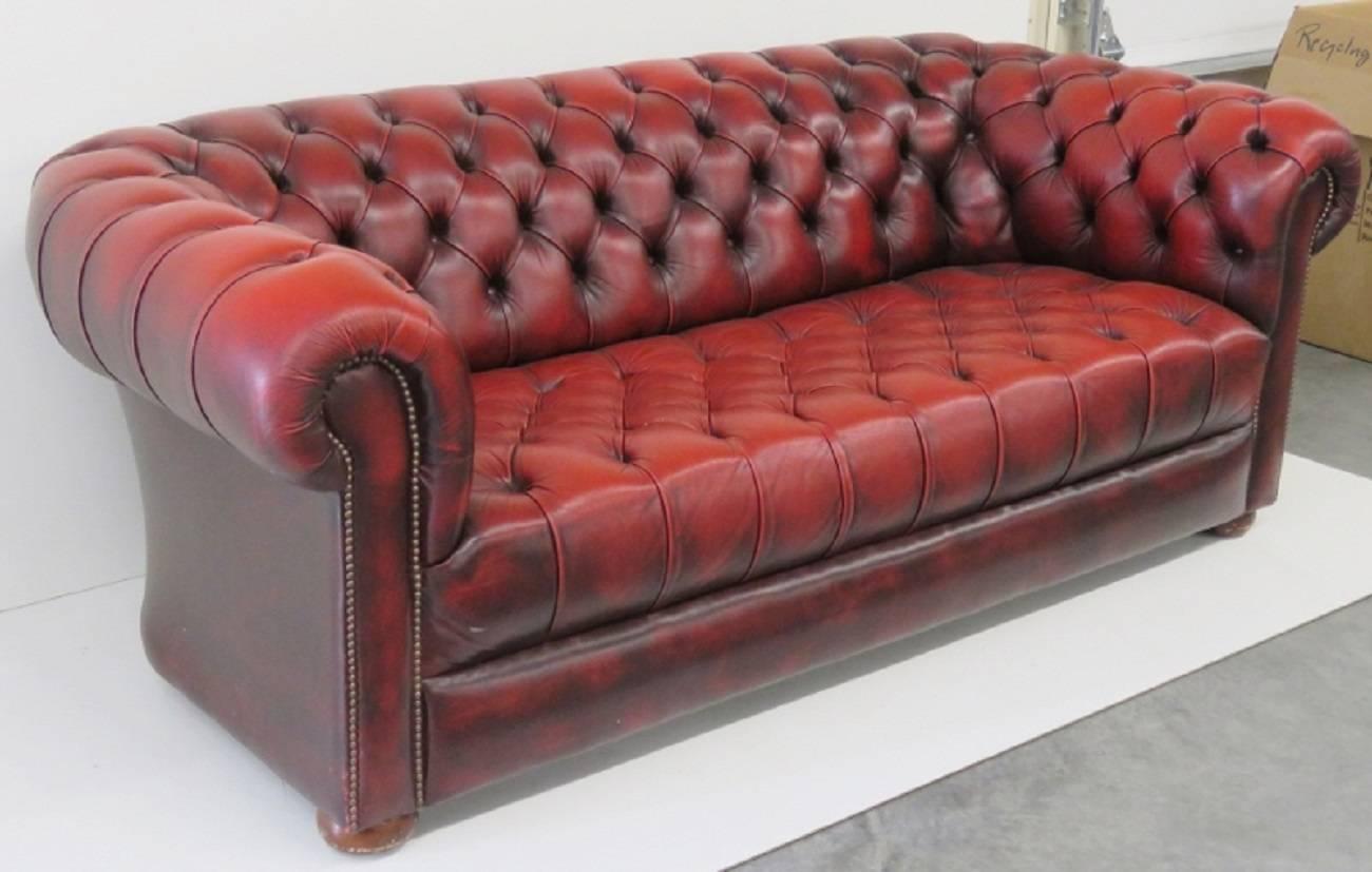 Red tufted leather upholstery with bun feet.