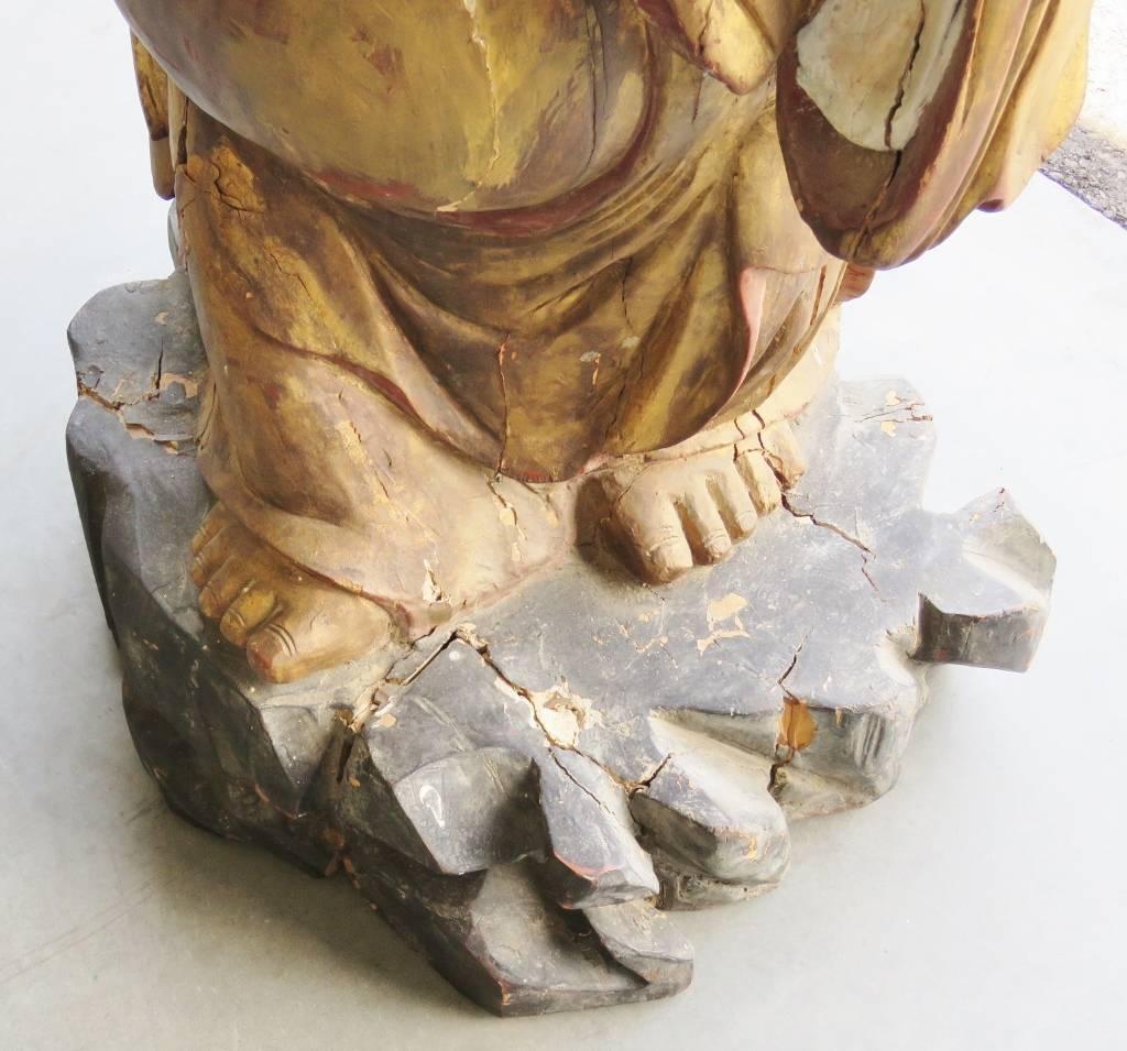 This is a wonderful carved wooden buddha with an ancient aged gilded surface. The carving has age cracks and paint losses that add to the character of this very happy buddha. 