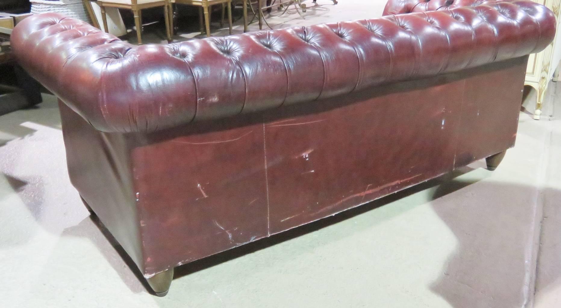 Red leather tufted upholstery. Wood legs with tacked frame.
