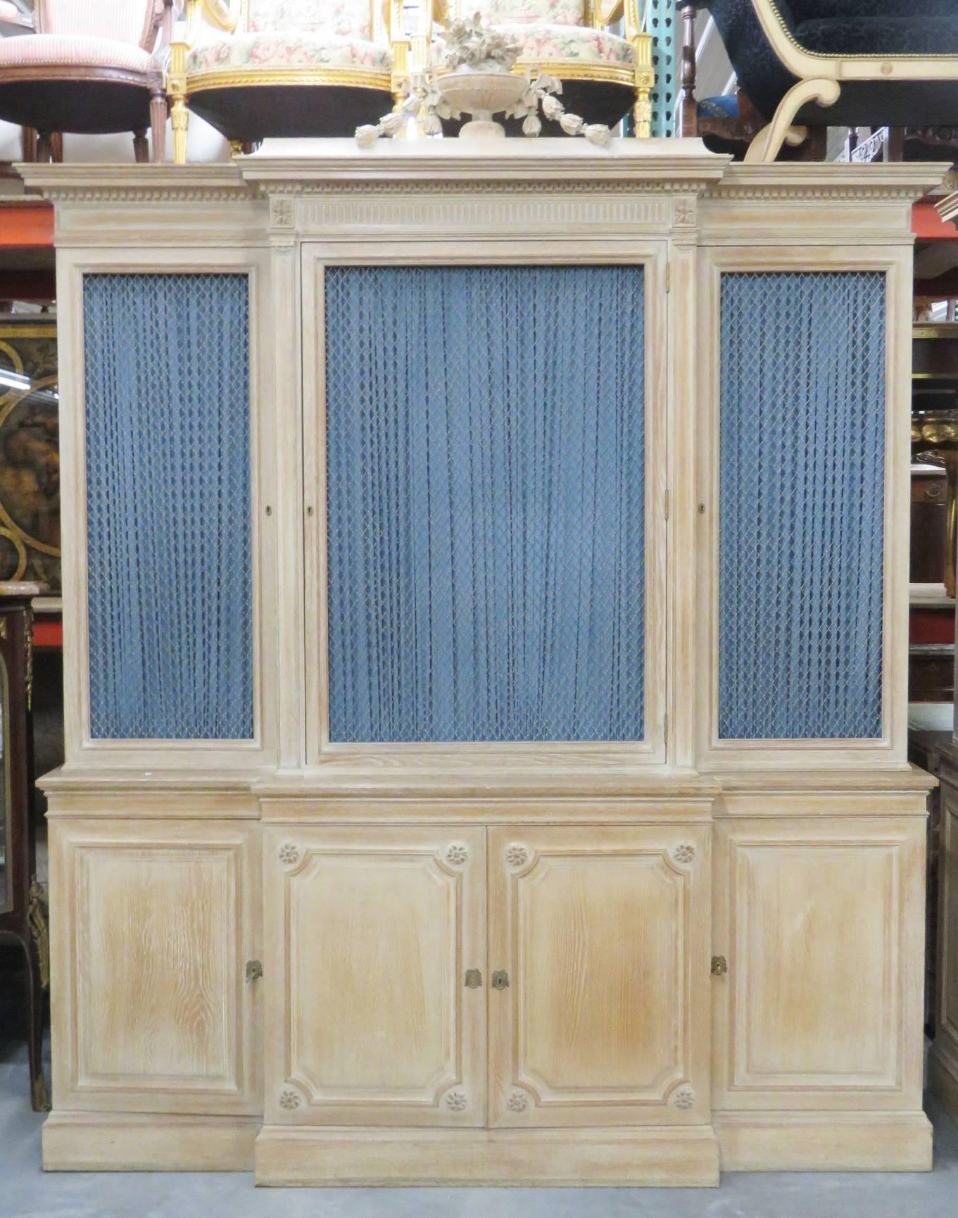 Stamped Jansen. Blond carved frame with carved urn crest and rosettes. Chicken wire front doors with blue curtains. Shelves inside for storage.