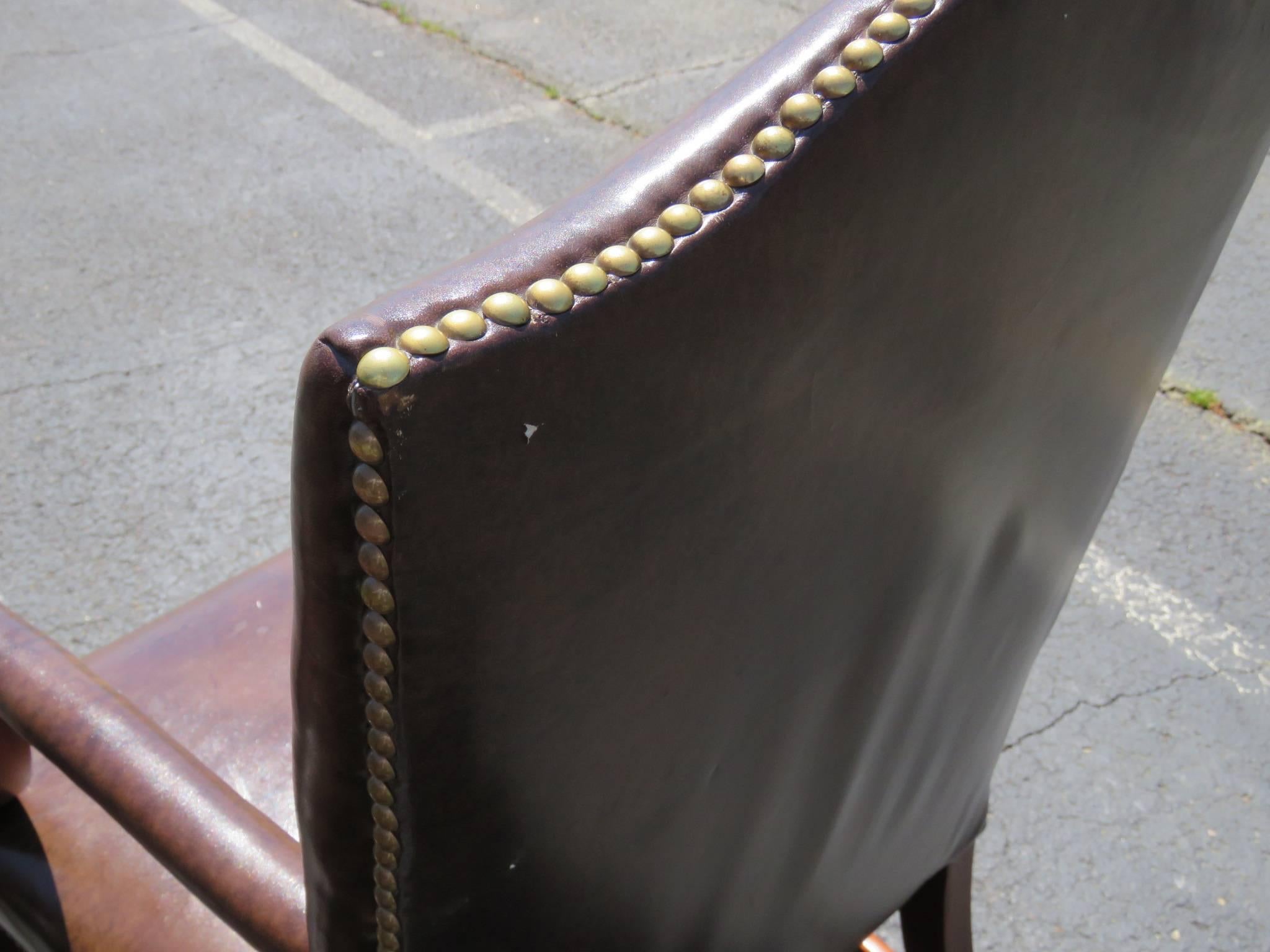 Carved frame. Brown Naugahyde upholstery. Tacked bottom.