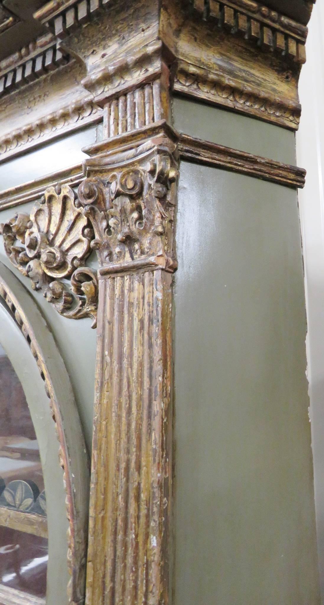 Distressed green painted and gilt carved frame. Wood shelves. Lions heads and floral decoration.