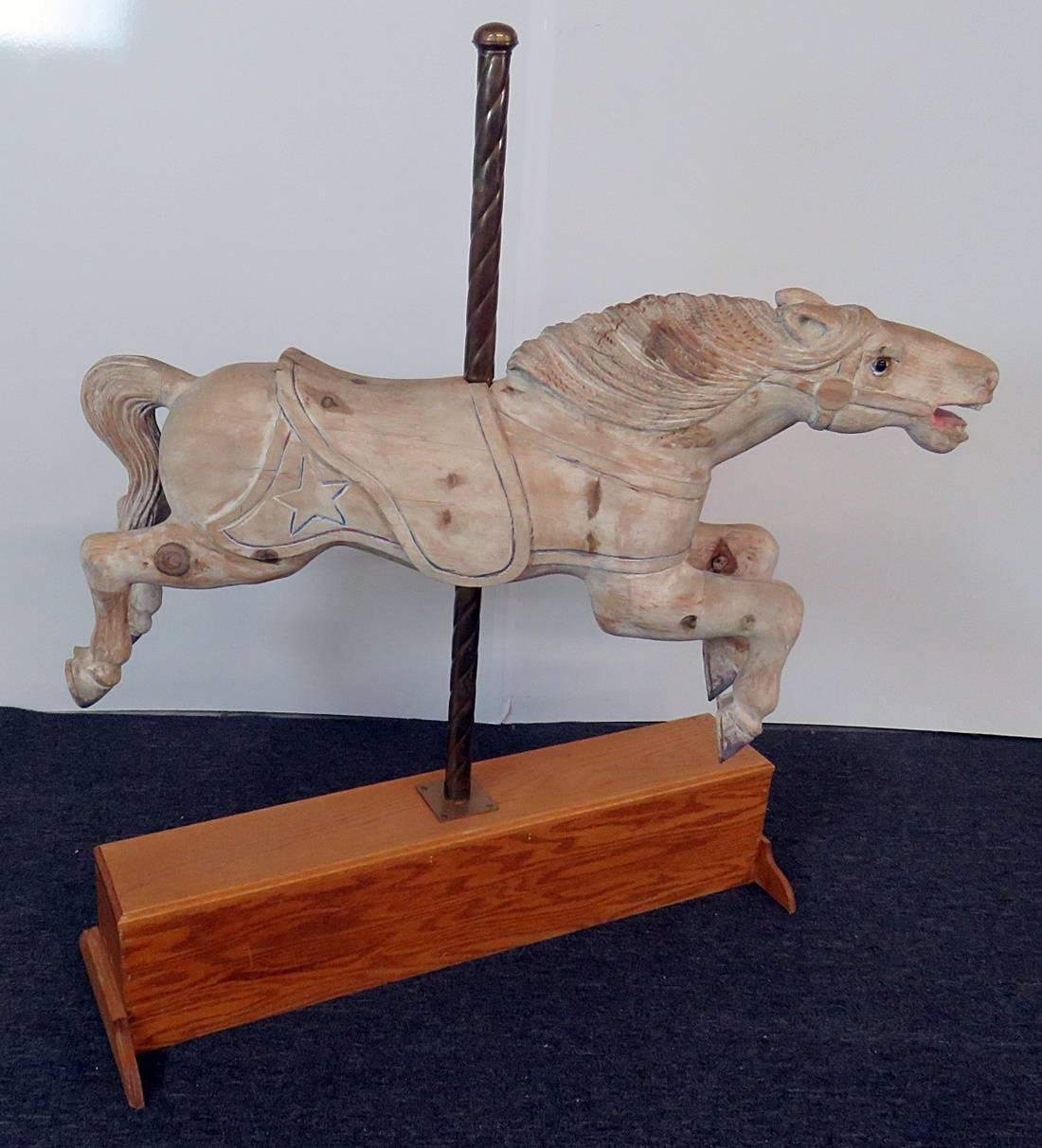 Distressed carousel style carved wood horse with a brass pole on a wood base.