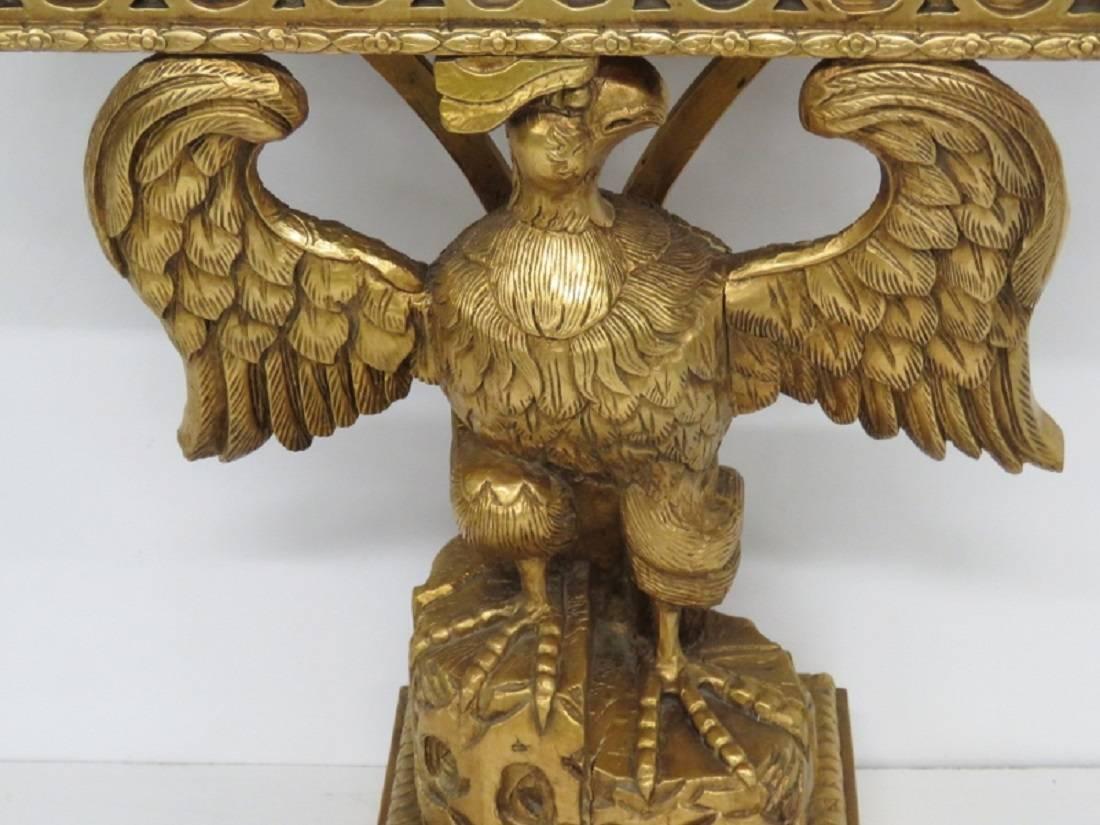 Console has a carved giltwood base with eagle and a black granite top.