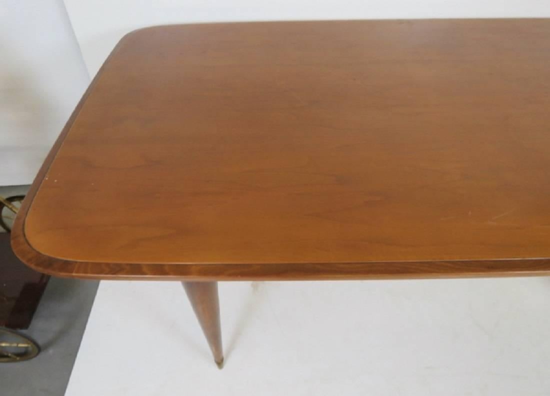 Italian modern walnut dining table. Cross stretcher base. Brass feet.