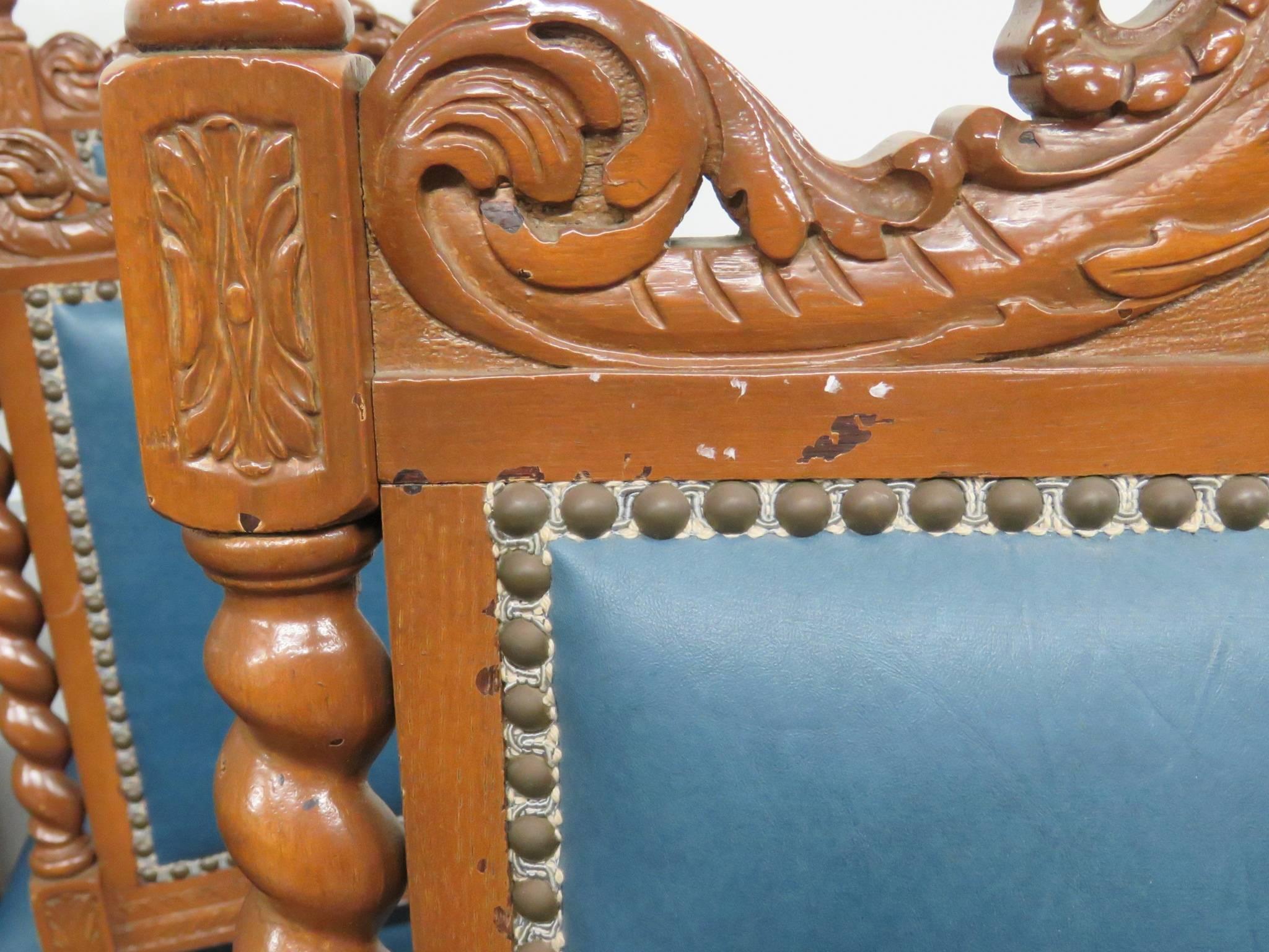 Dining chairs are intricately carved with griffins, barley twists and plumes. Dining chairs have blue Naugahyde with brown painted frames.