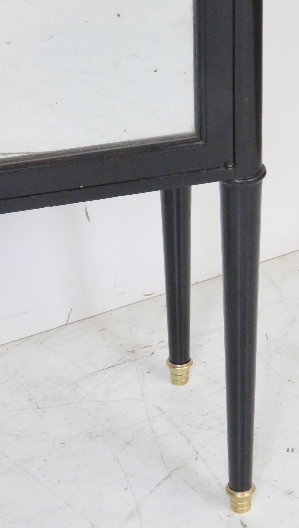 Ebonized lacquered finish with mirrored doors. Brass gallery and capped feet with marble top.
