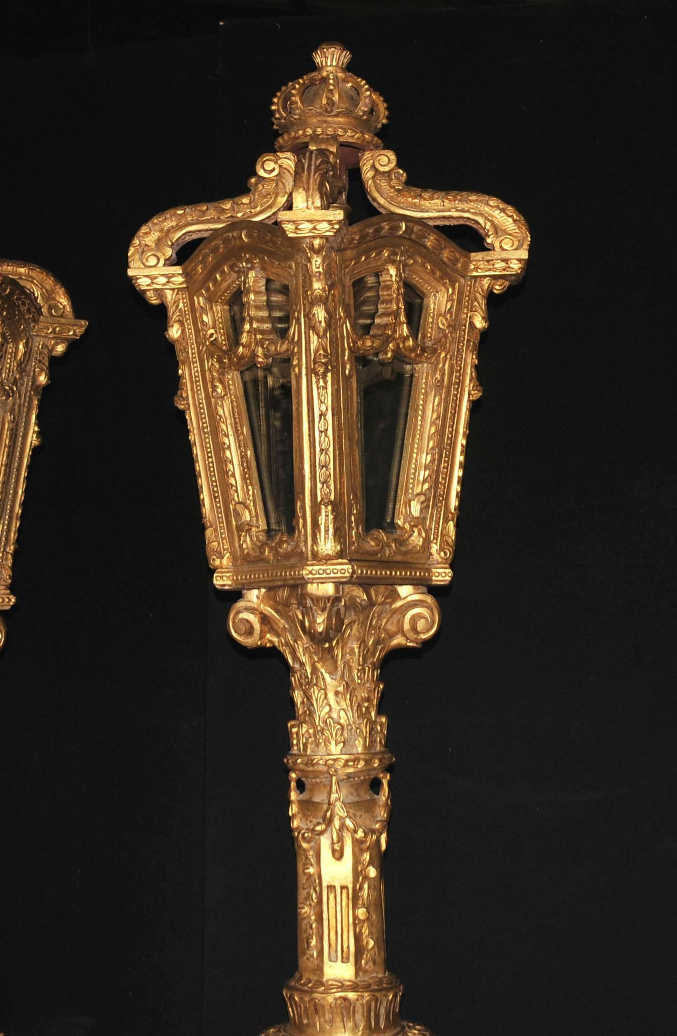 Pair large pair of Italian giltwood tall lamps or lanterns

Almost like a very elegant pair of street lamps, these stands in at over 8 feet tall (261 cm).
They are hand carved and the details are exquisite, very intricate and florid.
Surmounted