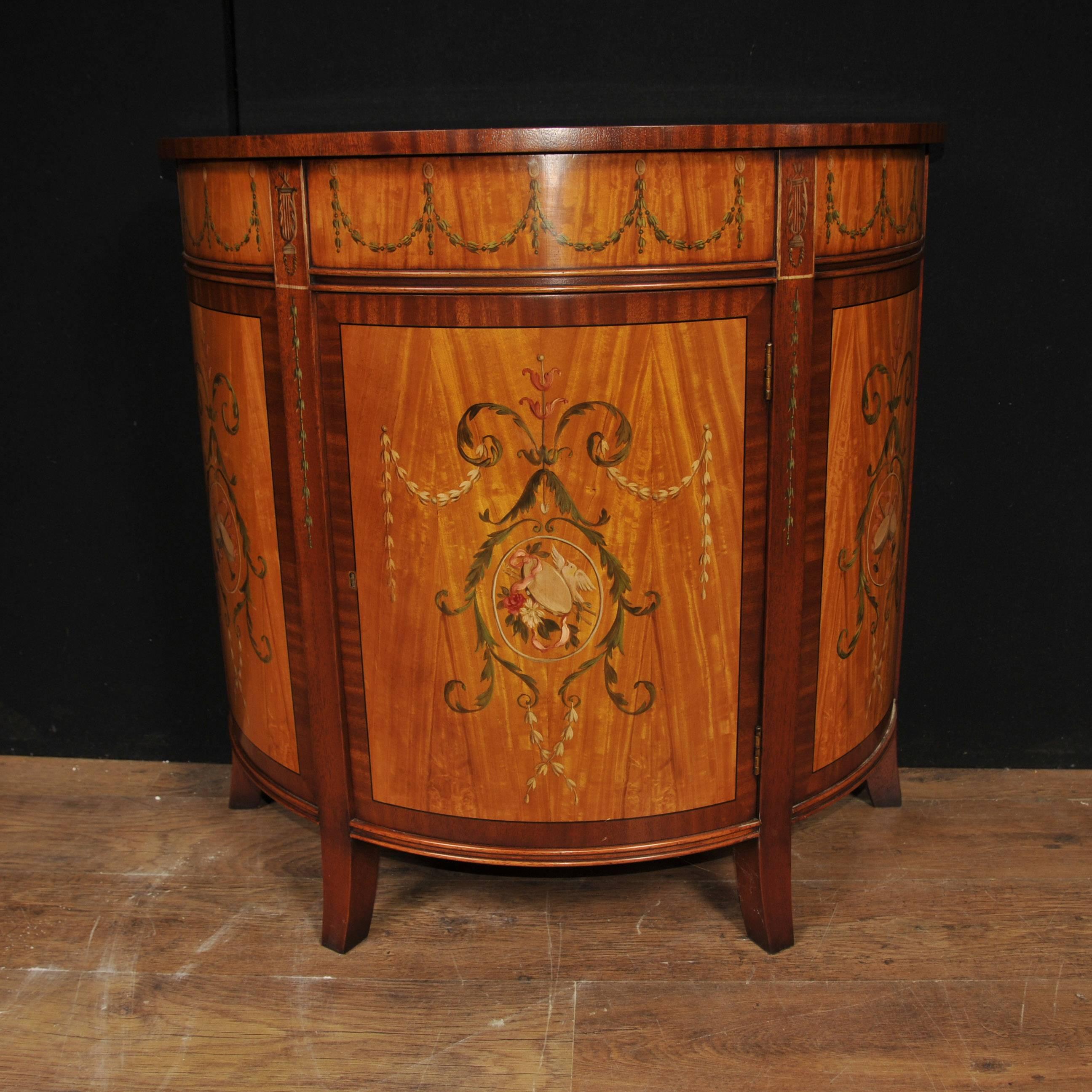 Gorgeous single Regency style painted cabinet in satinwood with rosewood banding.
High end luxury piece of quality cabinet of demi lune (half moon) form.
Love the hand painted designs including sashes, floral motifs and other Sheraton