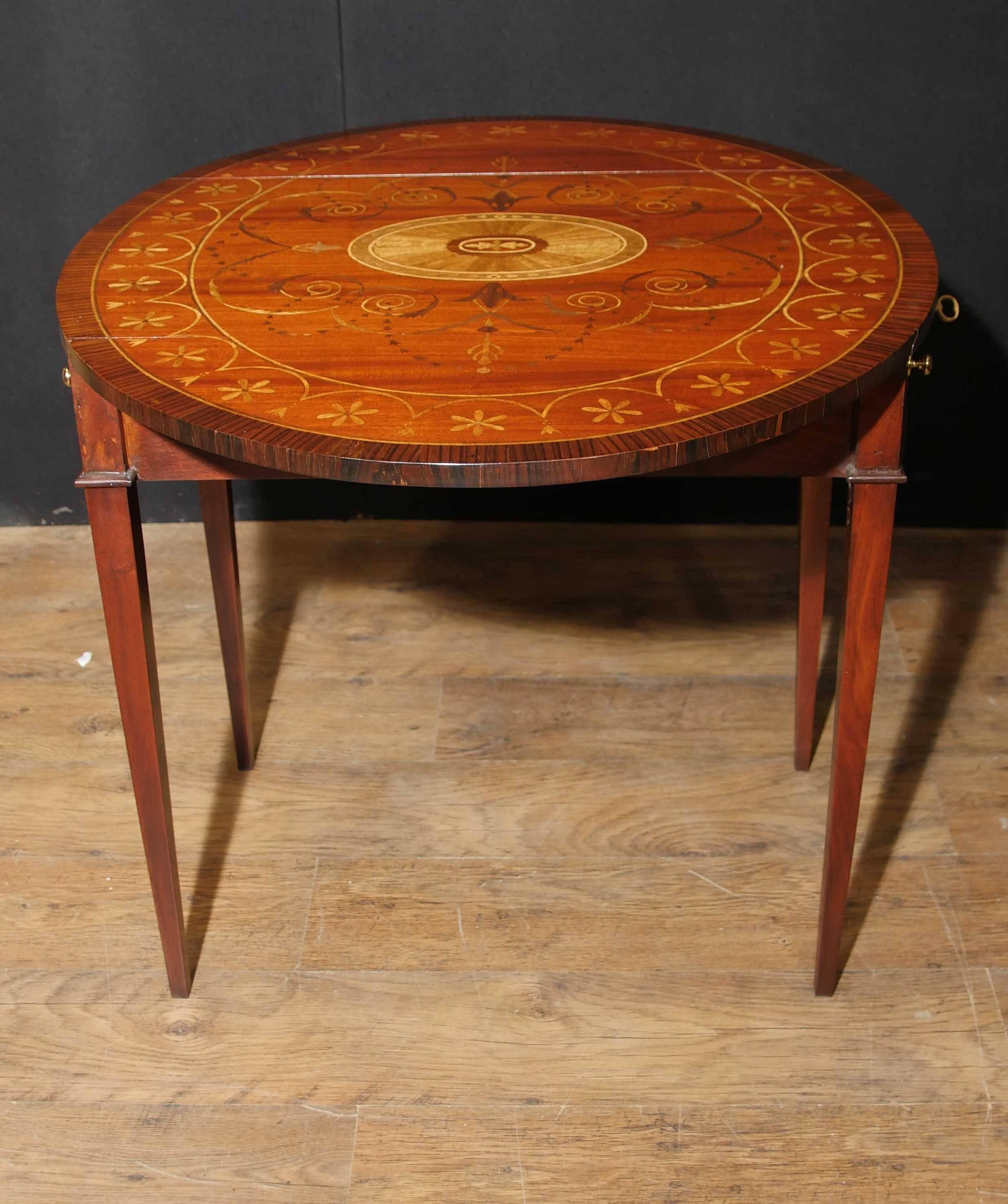 Gorgeous Sheraton style Pembroke or drop leaf table in mahogany and rosewood.
Profusely inlaid with exotic wood in marquetry with symmetrical patterns.
The Pembroke table was named for the Earl and Countess of Pembroke who first commissioned this