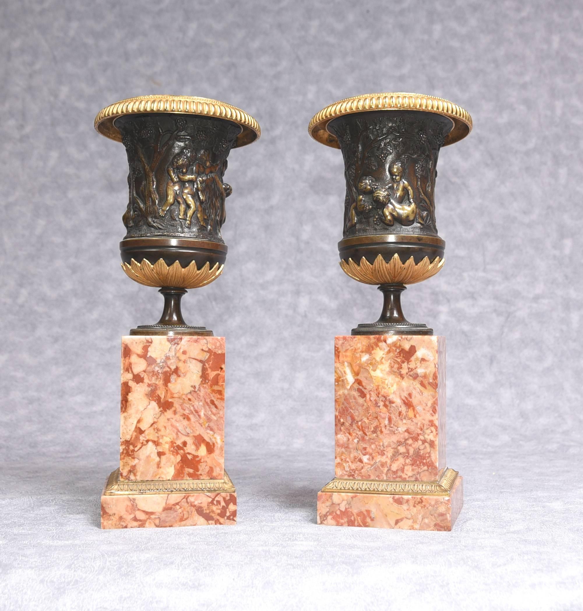 Gorgeous pair of Italian antique bronze urns on marble base
Classic campagna form to the urns with cherub relief frieze to outer surface
Stand on the squared marble pedestal bases with ormolu trim
We date this pair to circa 1950 and they are of