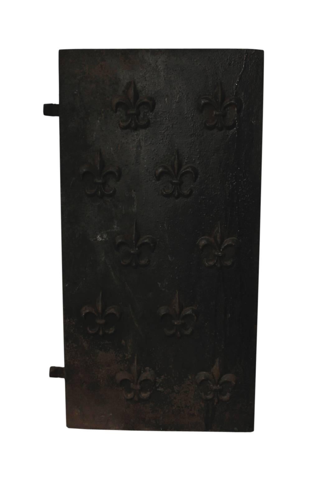 A rustic, cast iron fireplace liner, with fleur-de-lis relief pattern. The three pieces fit together via wedges on the outer panels, which fit into notches on the middle panel. Individually, the dimensions of the outer panels are 15