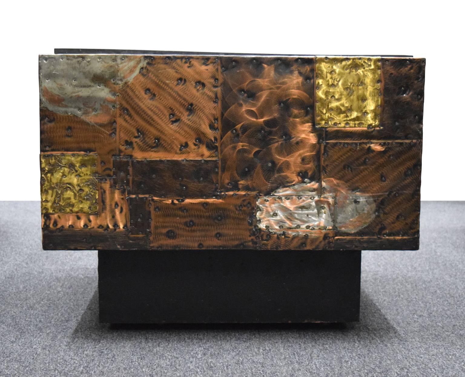 Listed here is a cube table, with a slate top and a patchwork of bronze, copper and pewter around the sides. It was built with hidden casters for greater mobility.