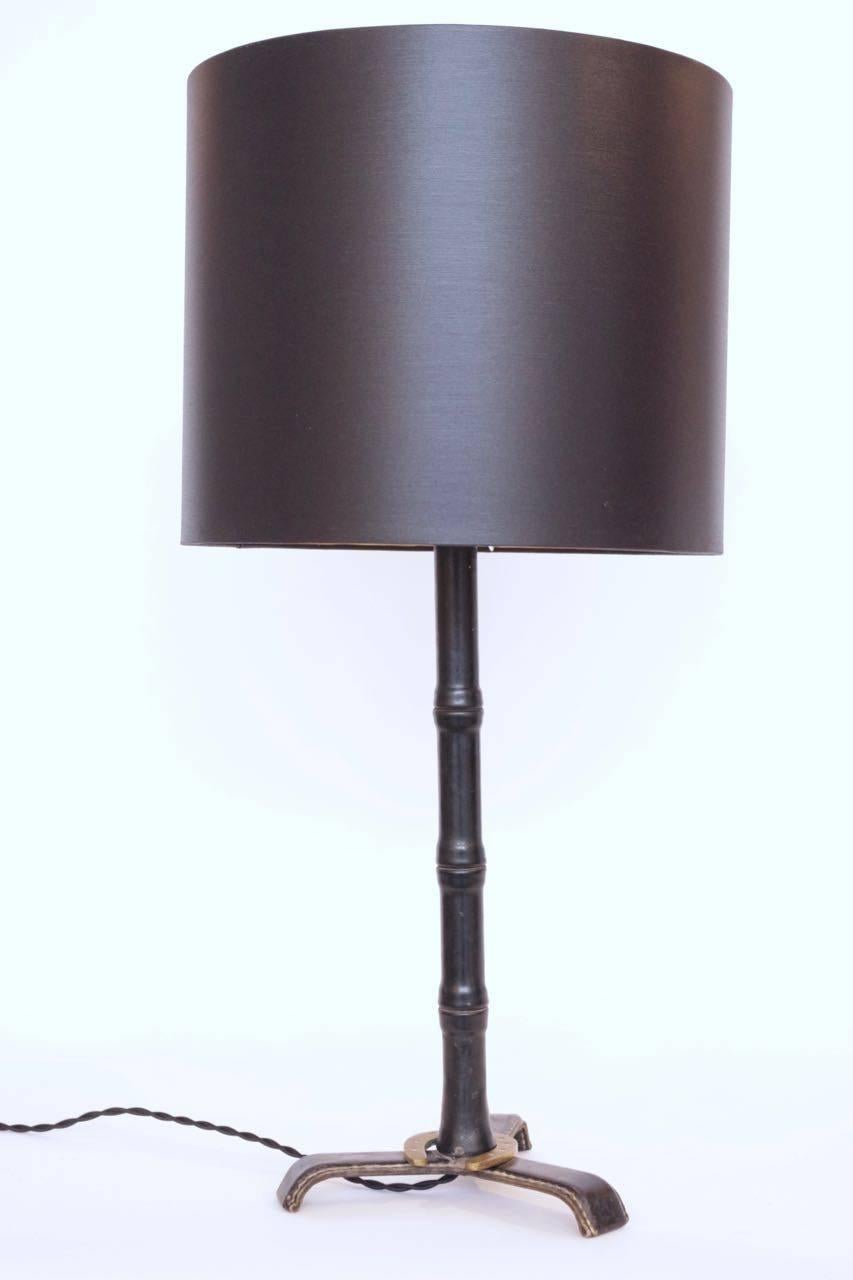 Jacques Adnet black leather table lamp decorated with a gilded horseshoe.