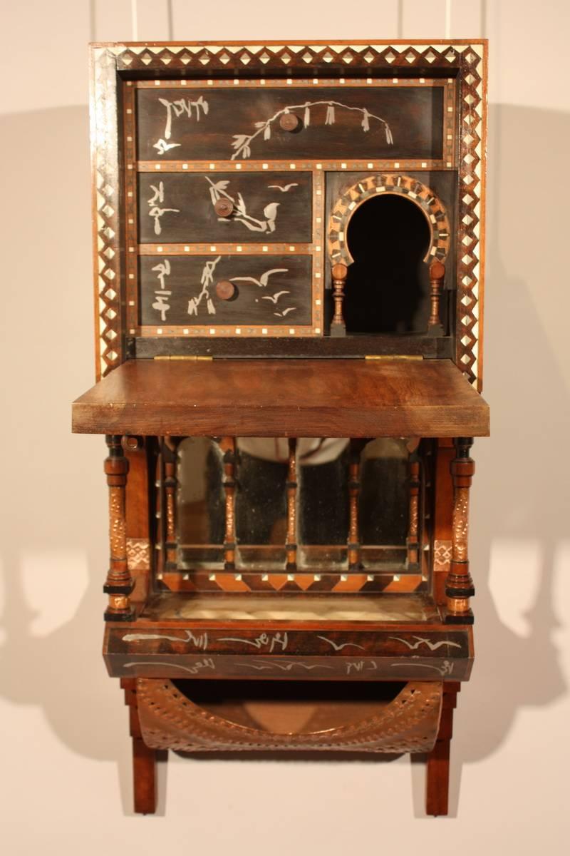 Carlo Bugatti wall cabinet,

circa 1900.
Italian walnut, ebonized wood with white metal inlay, copper, bone inlay, vellum, brass and silk tassels.
Features one drop-front door concealing divided storage and three shallow drawers.

.