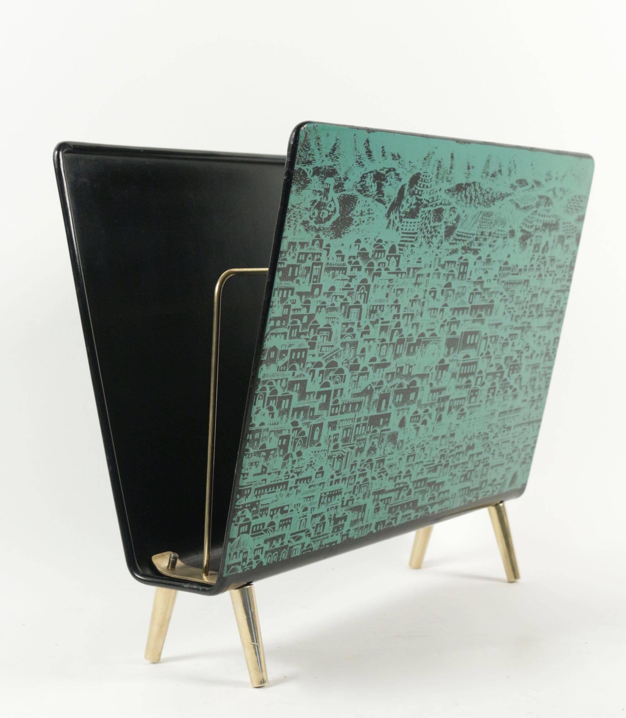 Porte-revues, vers 1960. Décor sérigraphié d'une vue de Jérusalem sur tôle laquée noire, petits pieds fuselés en laiton.
Black metal lacquered and lithographically printed with a green Jerusalem view.
Brass feets and a divider in the center