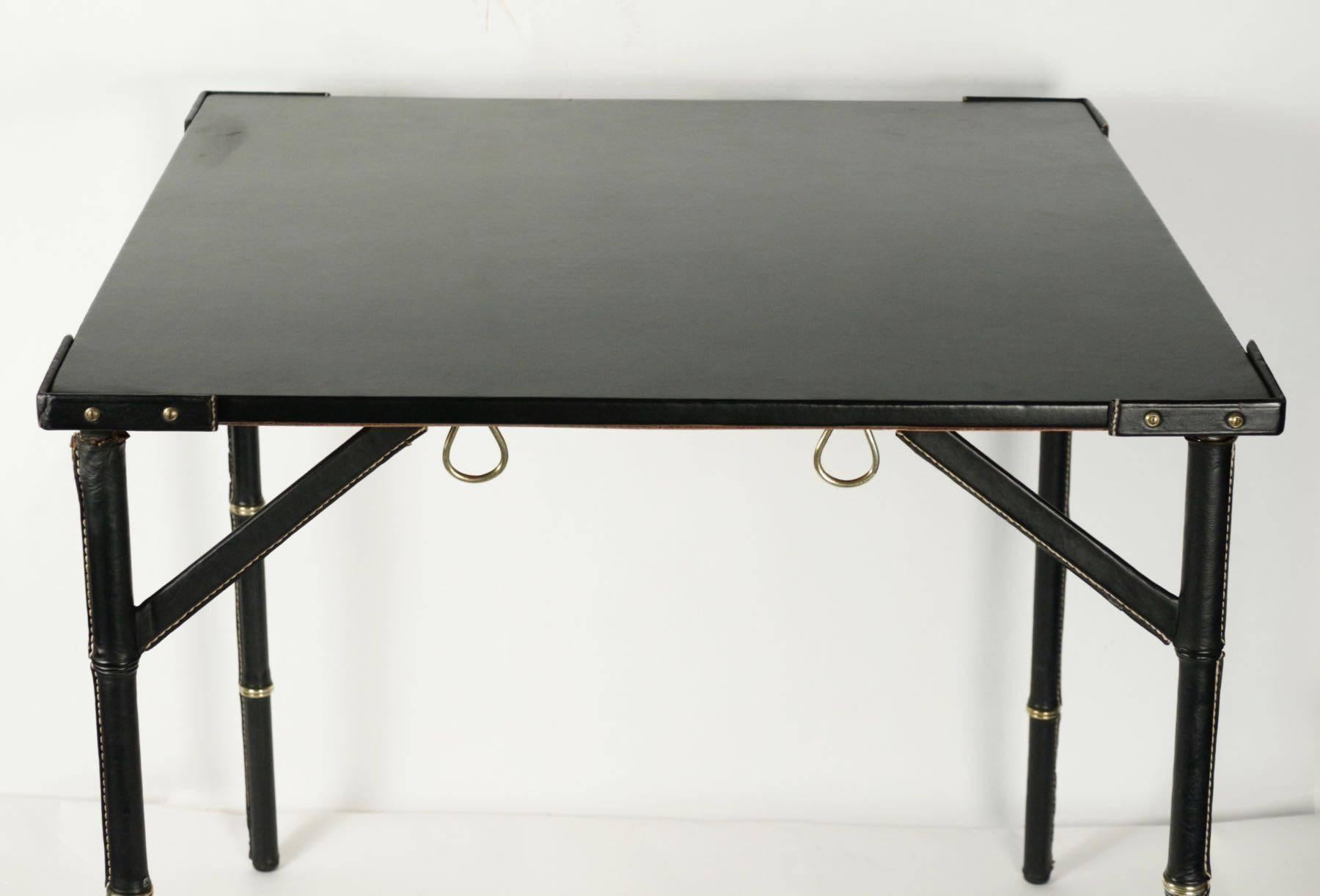 Jacques Adnet's black leather folding game table.
Bamboo style decorated with brass rings,
circa 1950.
Dimensions: 76.5 x 76.5 cm, height 73.5 cm.