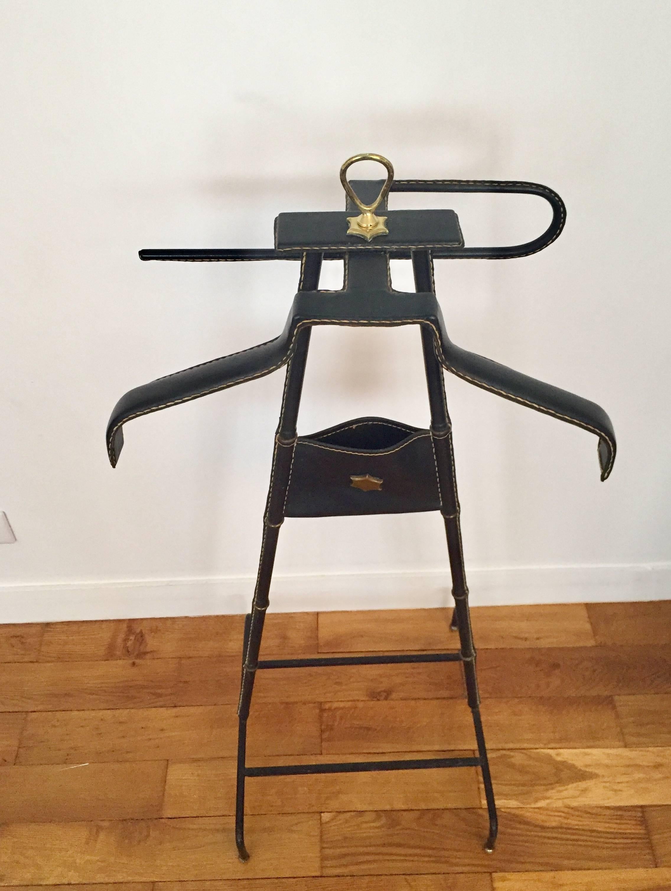 Black leather valet by Jacques Adnet decorated with two brass stars: one on the top of the valet and the second on a central pocket, 
circa 1950
Great original condition
Measures: Height 106 cm width 45 cm depth 39 cm.