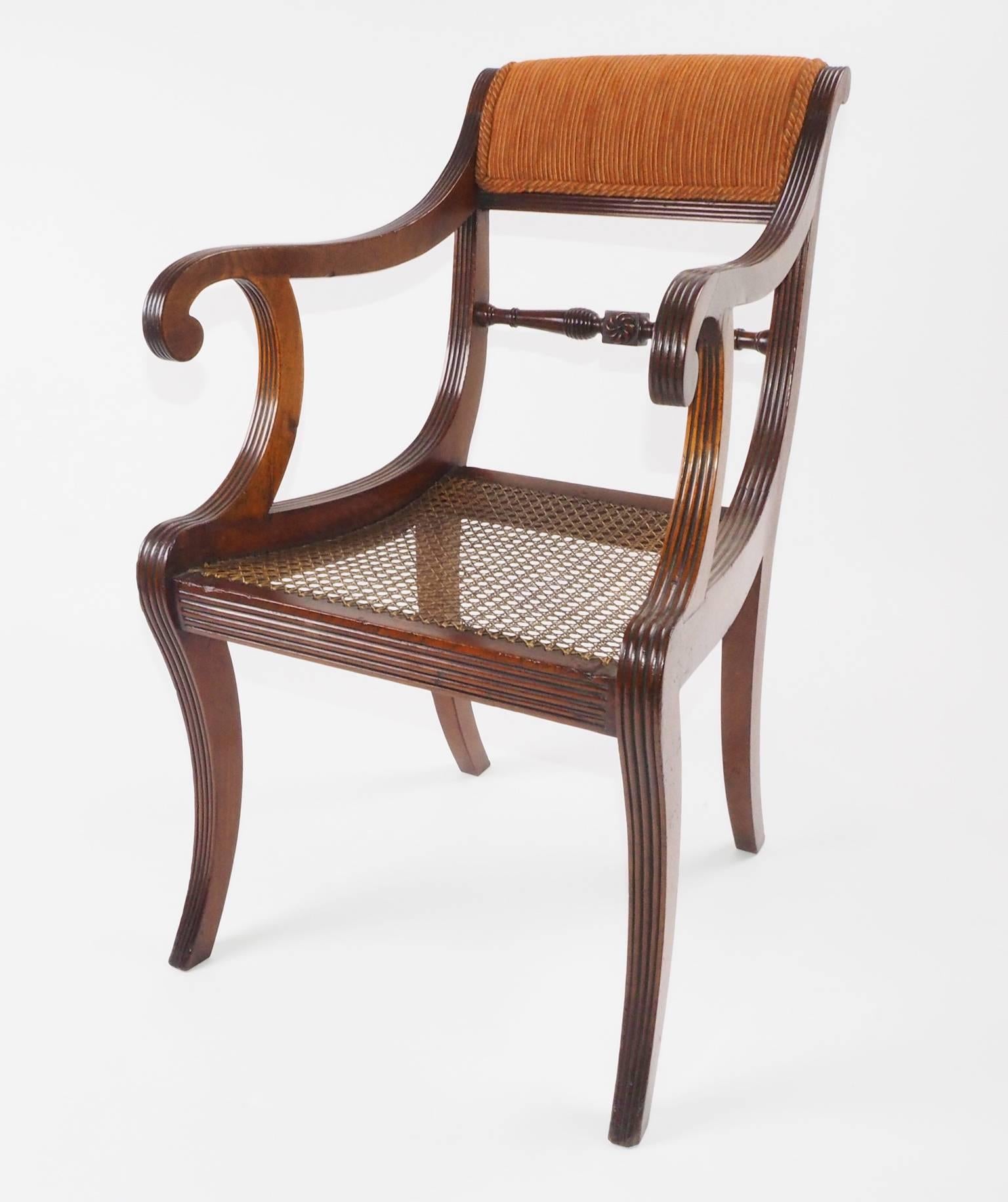 A finely reeded petite elbow chair with old, possibly original caning. It is entirely of
mahogany. Its elegant sabre legs are finely reeded and well proportioned. The underside of the 
front bar has the journeyman's stamp 'BC'. Gillows allowed