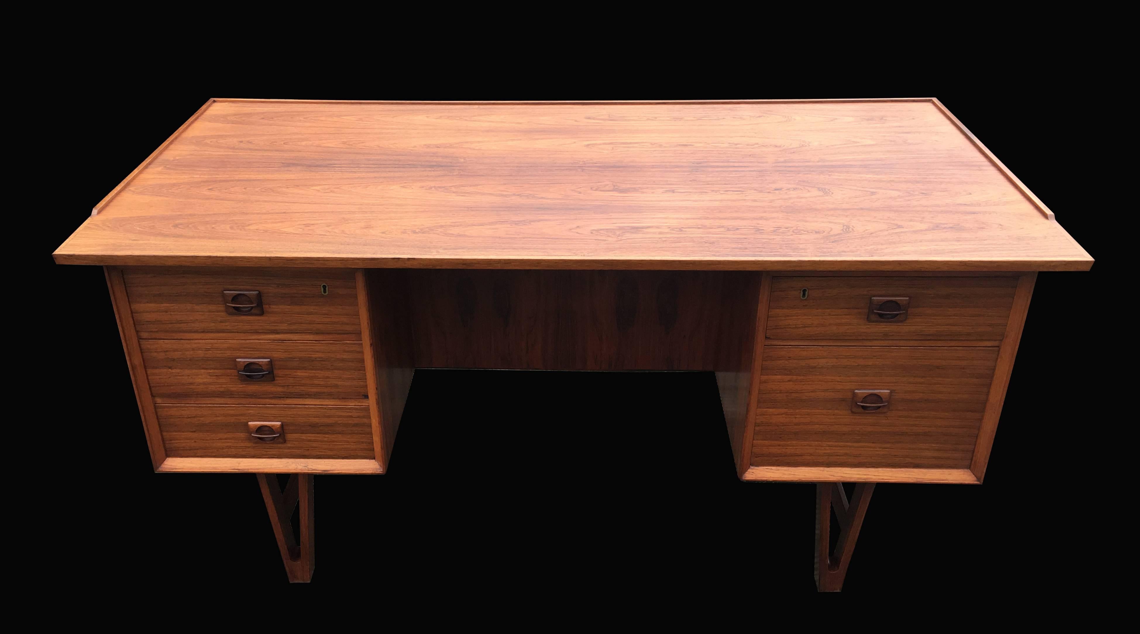 A super little unusual Danish rosewood desk with open 'V' shaped legs, three drawers on the left and one large and one small on the right, and open cupboards either side of the reverse side and a mirror back cupboard in the center.
All has been