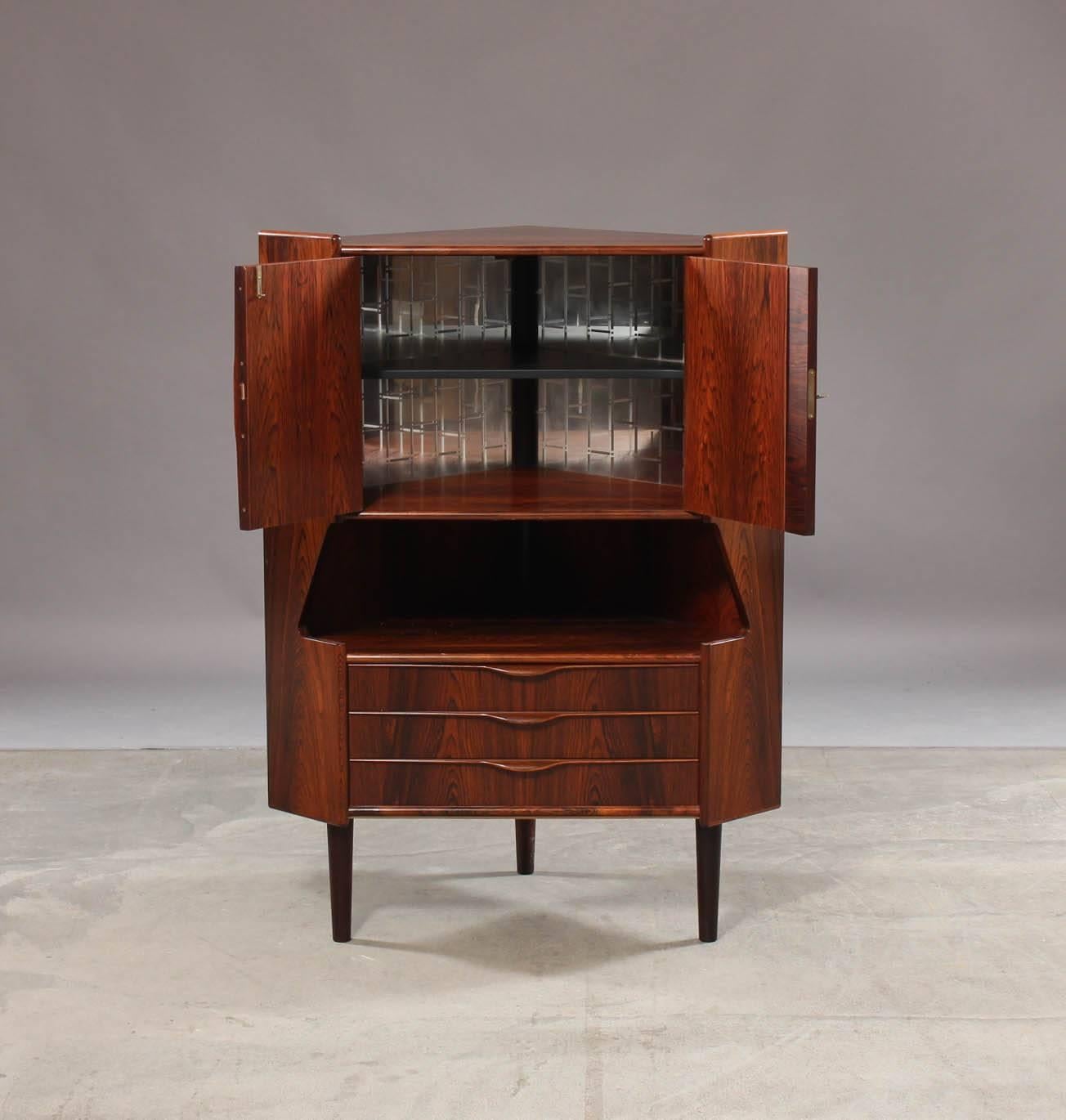 Beautifully figured rosewood corner cabinet by Gunni Omann, the interior of the top with original mirrored back interior intended for use as a bar, so the top drawer has a serving slide above it.