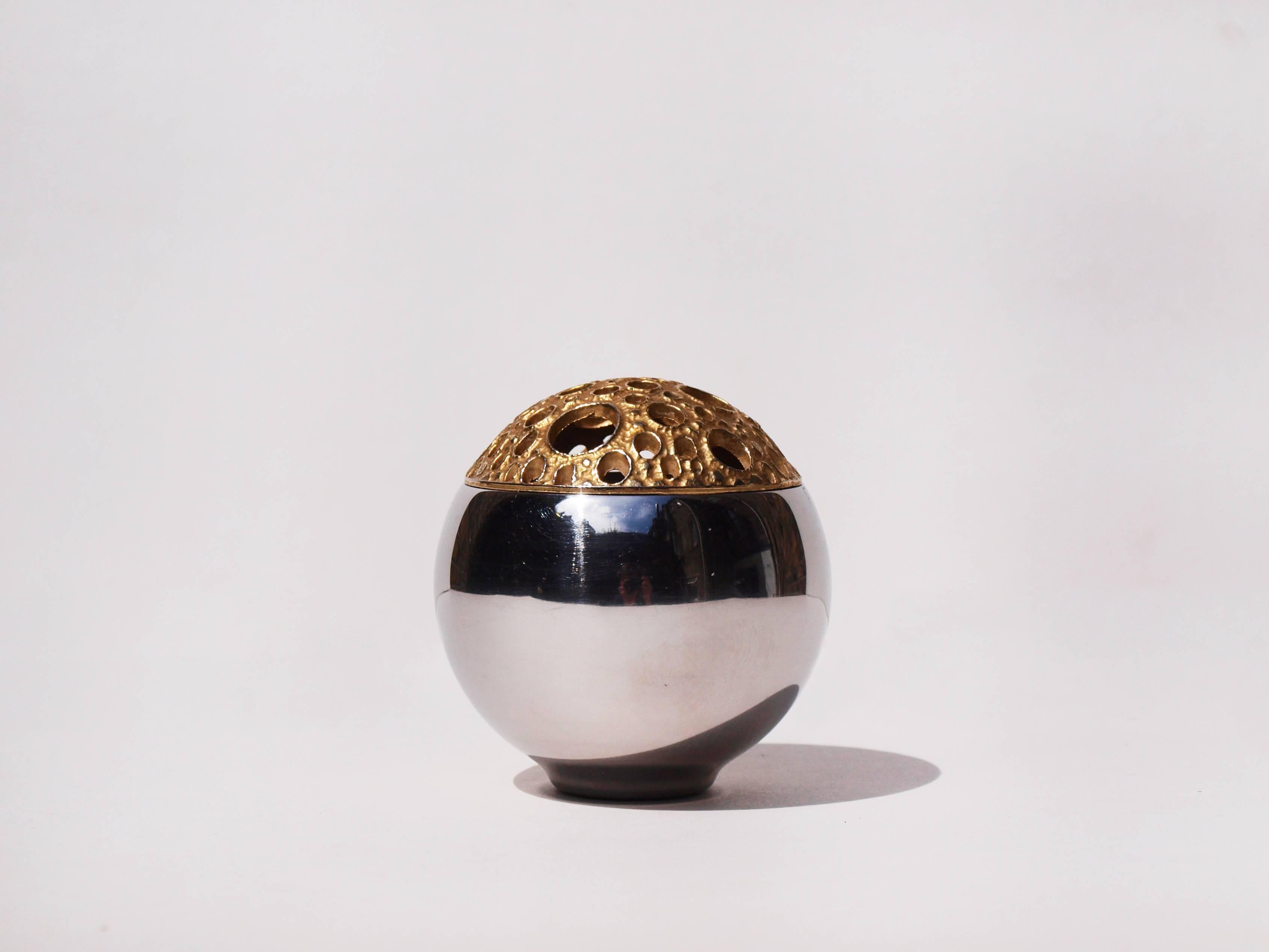 This stainless steel globe shaped vase was designed by renowned gold and silversmith, Stuart Devlin for Viners. Devlin worked with the company to produce collections of high end serveware. The Futurist vase features a gilded removable lid with
